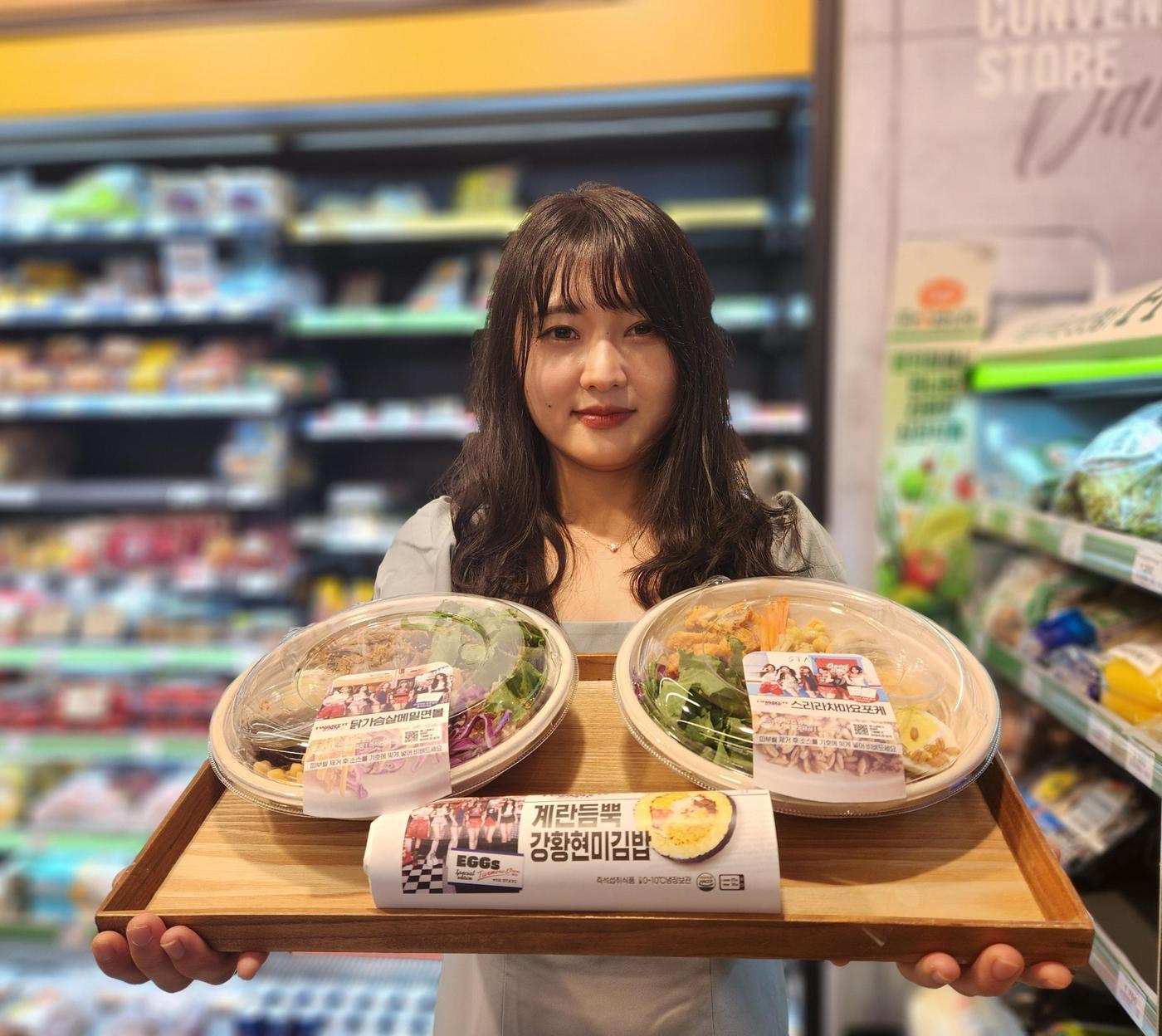 본문 이미지 - 모델이 '스테이씨' 컬래버 간편식과 디저트 2탄을 소개하고 있다.(이마트24 제공)