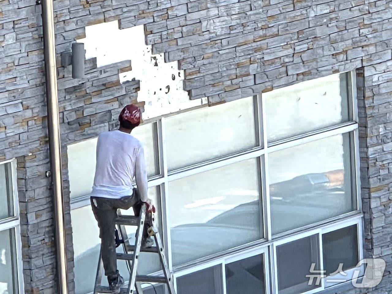 본문 이미지 - 한 건설 근로자가 외벽 석재타일이 떨어진 보은군의회 청사 외벽을 살펴보고 있다. /뉴스1 