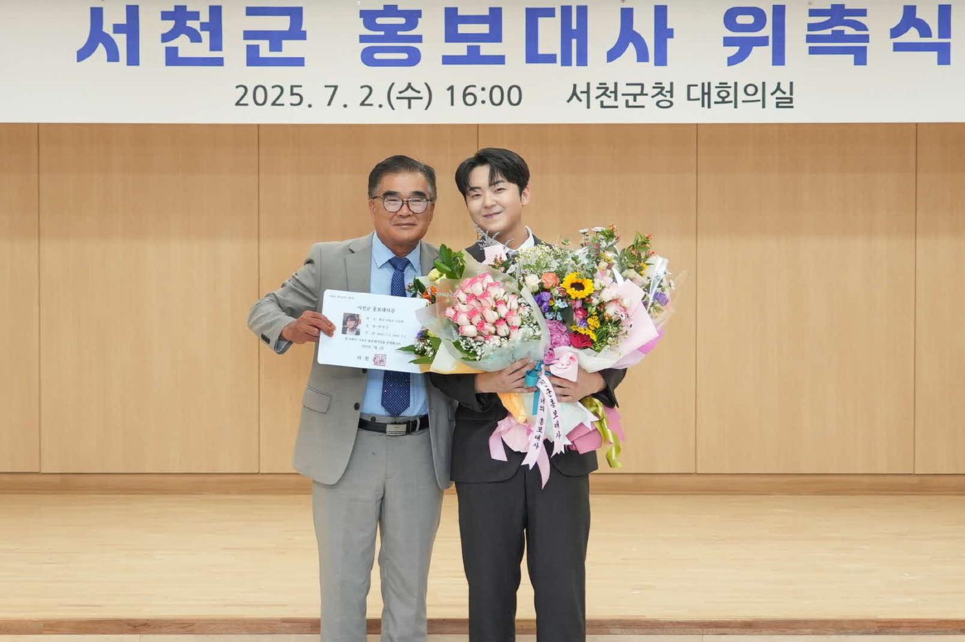  김기웅 서천군수(왼쪽)가 트로트 가수 박민수에게 1호 홍보대사 위촉장을 수여하고 기념촬영을 하고 있다.(서천군 제공. 재판매 및 DB금지)2025.7.3/뉴스1