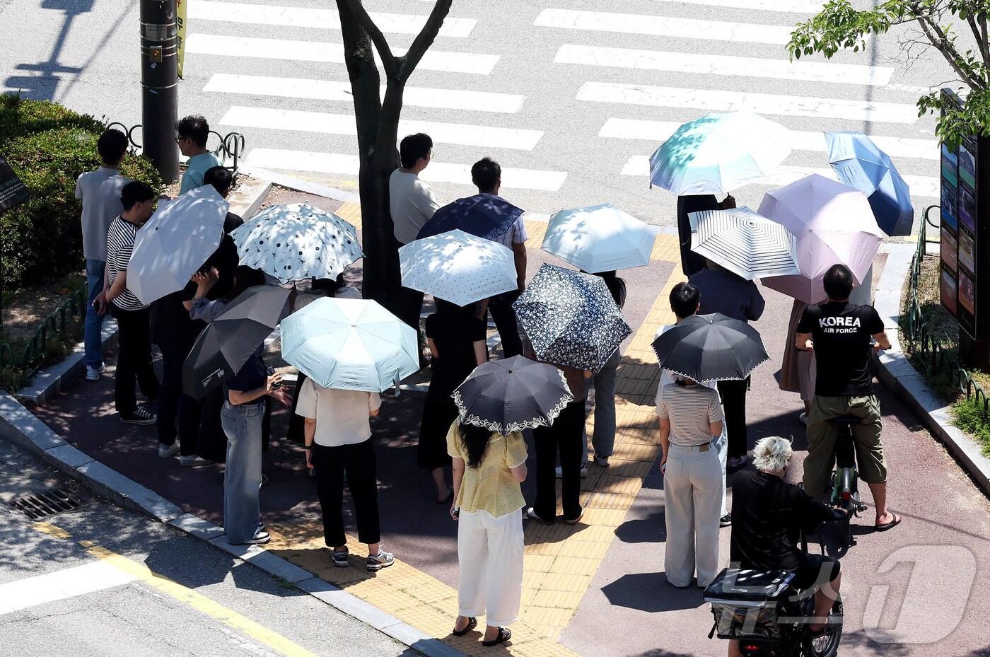찜통더위가 이어지고 있는 3일 광주 북구청 교차로에 구청 공직자들이 점심시간 양산을 쓰고 이동하고 있다. (광주 북구 제공. 재판매 및 DB 금지) 2025.7.3/뉴스1 ⓒ News1 박지현 기자