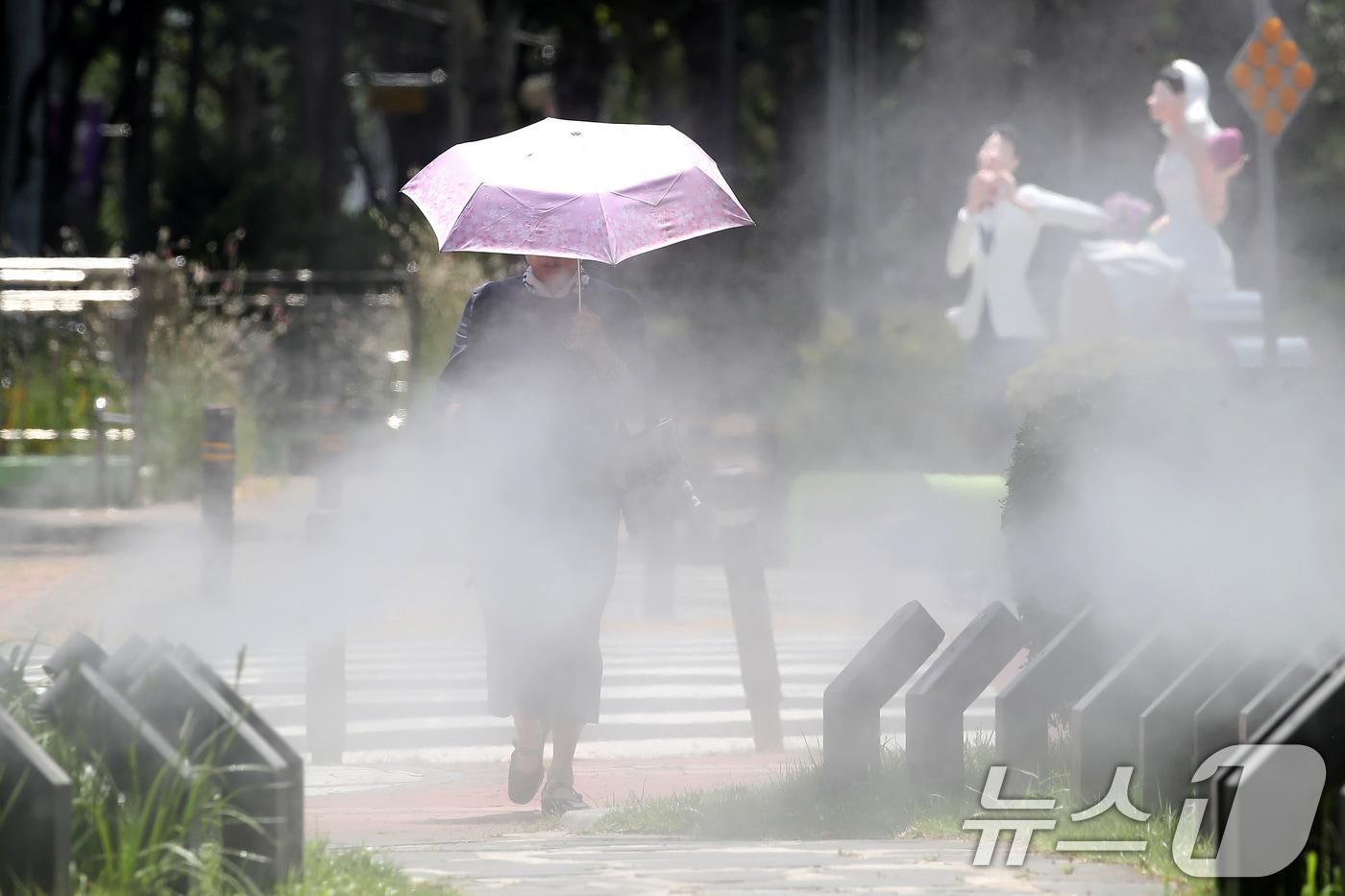 일주일째 폭염특보가 이어진 3일 대구 중구 김광석길 입구에 가동된 쿨링포그 사이로 양산을 쓴 시민이 걷고 있다. 2025.7.3/뉴스1 ⓒ News1 공정식 기자