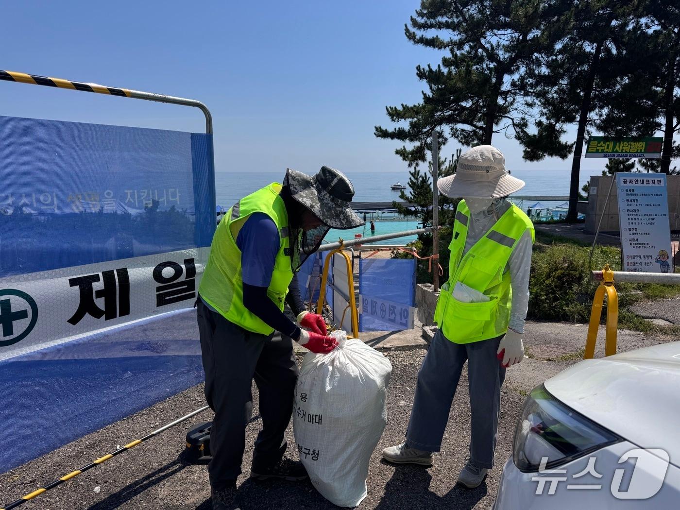 본문 이미지 - 30일 울산 북구 강동 몽돌해변 입구에서 &#39;바다환경지킴이&#39; 2명이 땡볕 아래 구슬땀을 흘리며 마대를 묶고 있다.2025.7.30./뉴스1 ⓒNews1 김세은 기자