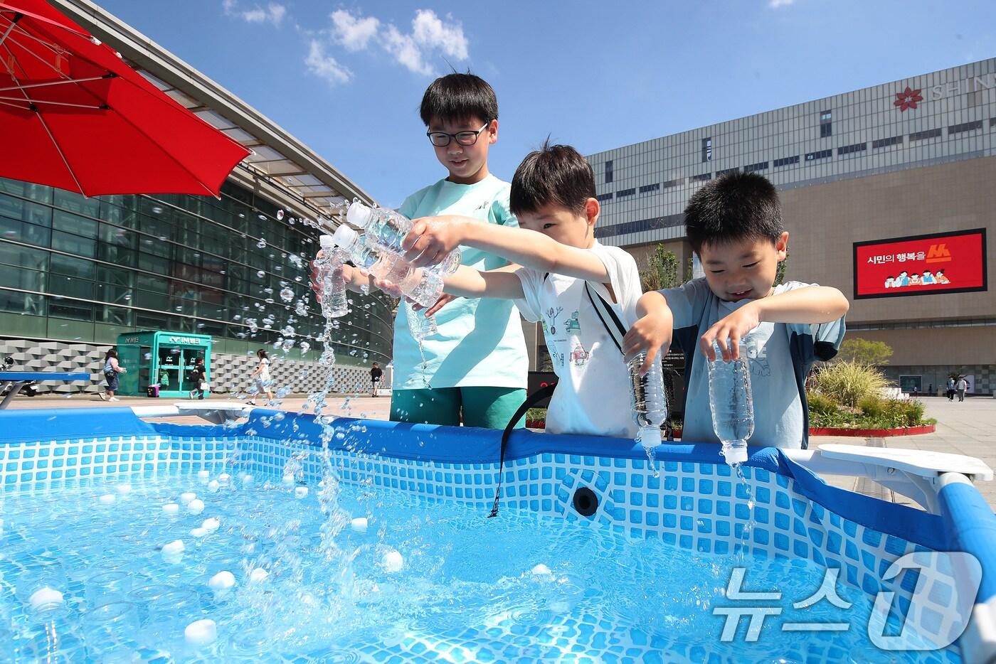 삼복더위가 절정에 달한다는 중복을 맞아 30일 오후 대구 동구 동대구역 광장에서 열린 '건강한 여름나기 캠페인' 현장을 지나던 어린이들이 얼음 수조에서 청라수를 꺼내고 있다.  2025.7.30/뉴스1 ⓒ News1 공정식 기자