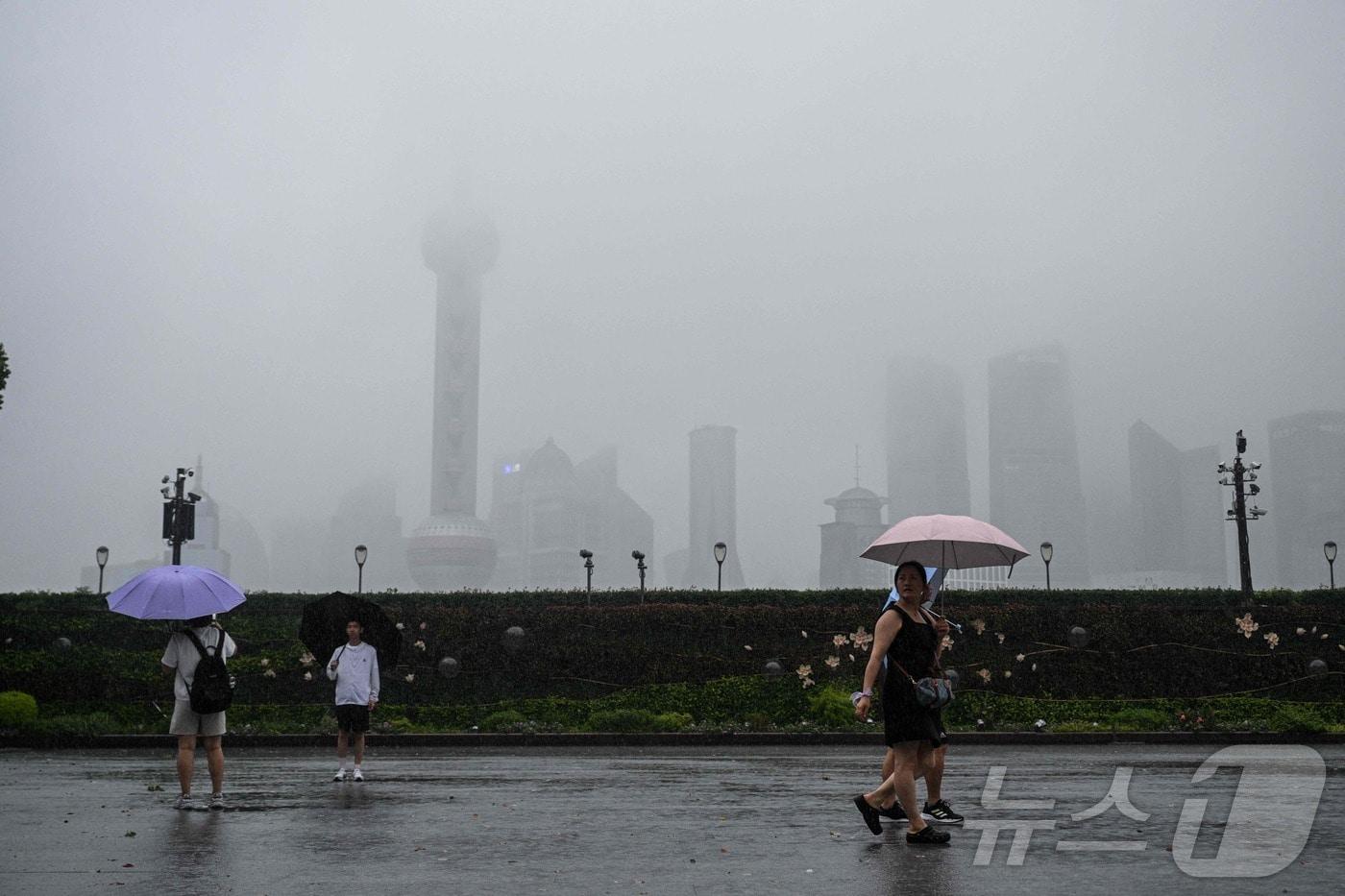 30일 제13호 태풍 ‘코메이’가 상하이를 관통하는 가운데, 황푸강 산책로를 시민들이 강풍과 폭우 속에서도 걷고 있다.2025.07.30. ⓒ AFP=뉴스1