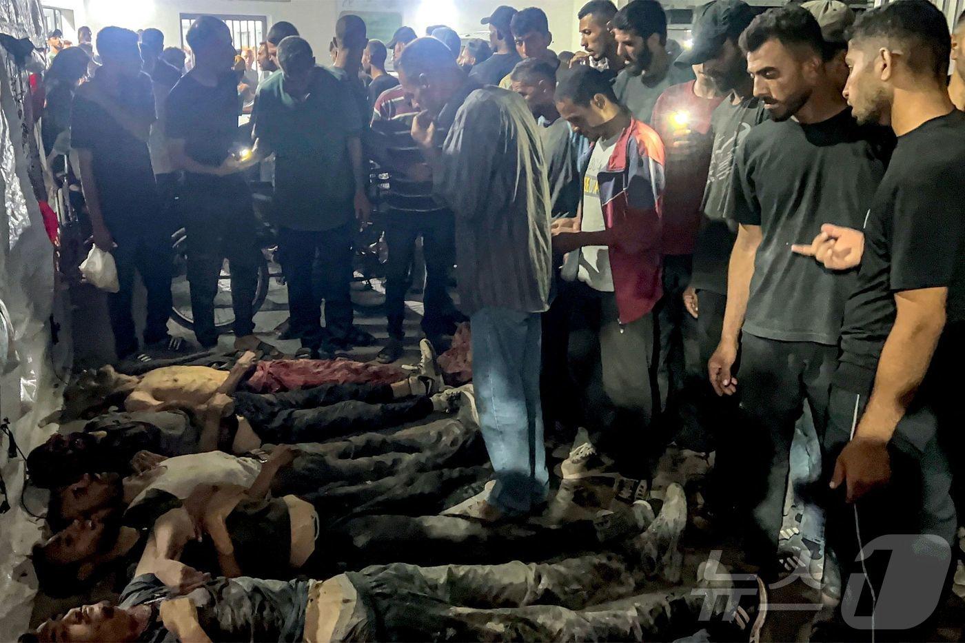 30일(현지시간) 가자시티 알시파 병원에 검문소를 통과하는 구호 트럭을 기다리다 이스라엘군의 발포로 숨진 희생자들 곁에 팔레스타인 주민들이 모여 있다. 2025.07.30. ⓒ AFP=뉴스1 ⓒ News1 윤다정 기자