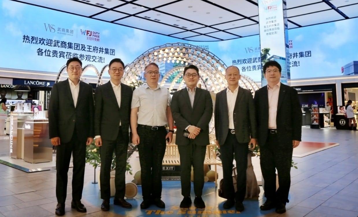 본문 이미지 - (왼쪽부터) 곽종우 신세계디에프 마케팅 담당, 양호진 전무, 판홍샹 우상그룹 동사장, 문현규 상무, 후용 왕푸징그룹 부총재, 윤기섭 코트라 우한무역관장이 신세계면세점 명동점 10층 아이코닉존 미디어파사드 앞에서 기념촬영 하고 있다. (신세계면세점 제공)