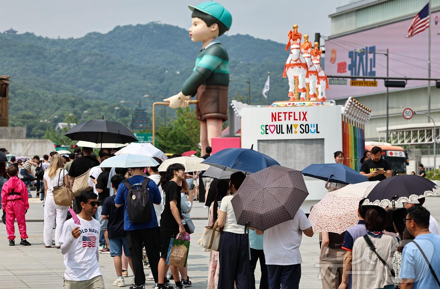 서울 종로구 광화문광장에 마련된 넷플릭스 오징어 게임 체험존에 관광객들이 양산을 쓰고 대기하고 있다. 2025.7.4/뉴스1 ⓒ News1 김도우 기자
