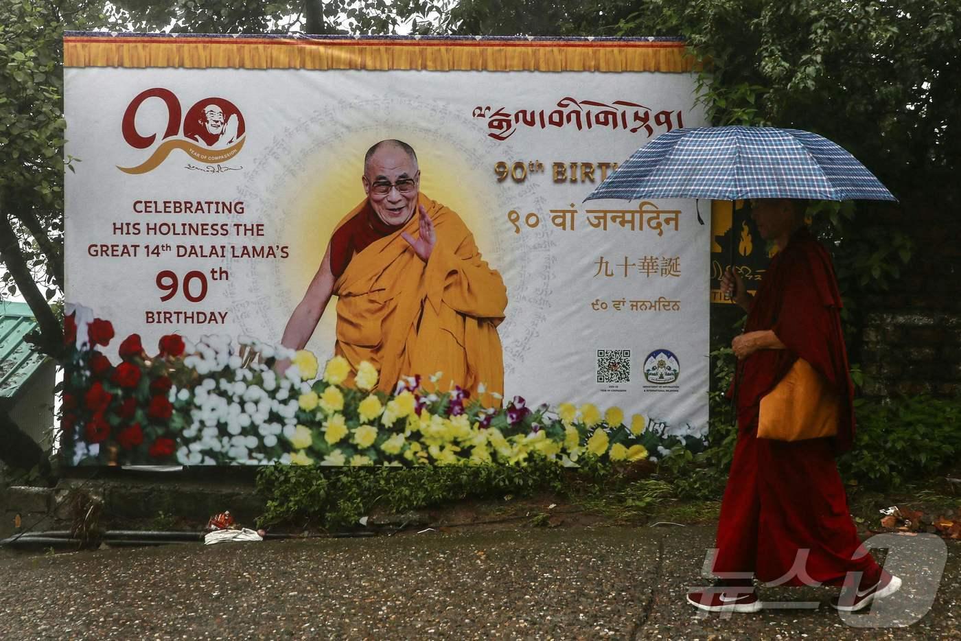 인도 북부 다람살라 근처 도시인 맥레오드 간즈에서 4일&#40;현지시간&#41; 한 승려가 티베트의 정신적 지도자 달라이 라마의 90번째 생일을 축하하는 한 현수막 앞을 지나고 있다.2025.07.04. ⓒ AFP=뉴스1 ⓒ News1 권영미 기자