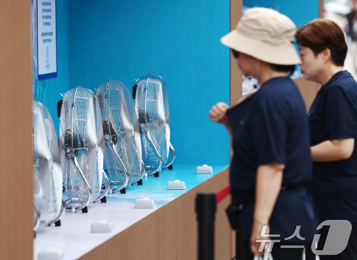 본문 이미지 - 절기상 본격적인 더위가 시작된다는 소서(小暑)이자 서울 전역에 첫 폭염경보가 내려진 7일 서울 광화문광장에서 더위에 지친 시민들이 선풍기 바람을 맞고 있다. 2025.7.7/뉴스1 ⓒ News1 김민지 기자