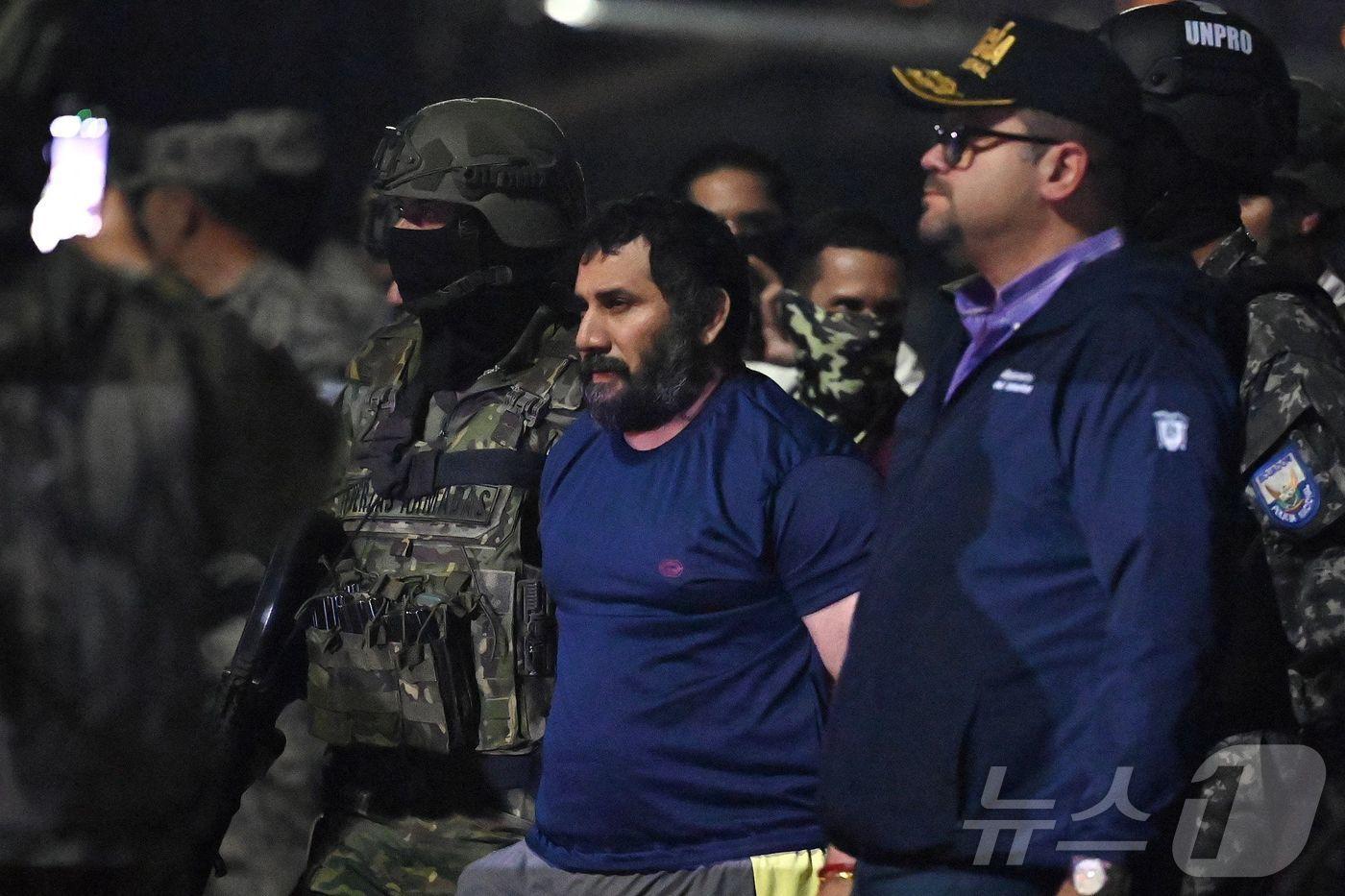 에콰도르 군·경에 의해 체포된 마약왕 아돌포 마시아스, 일명 피토&#40;가운데&#41;가 존 레임버그&#40;오른쪽&#41; 내무장관에 이끌려 호송되고 있다. 2025.6.25. RMY ⓒ AFP=뉴스1