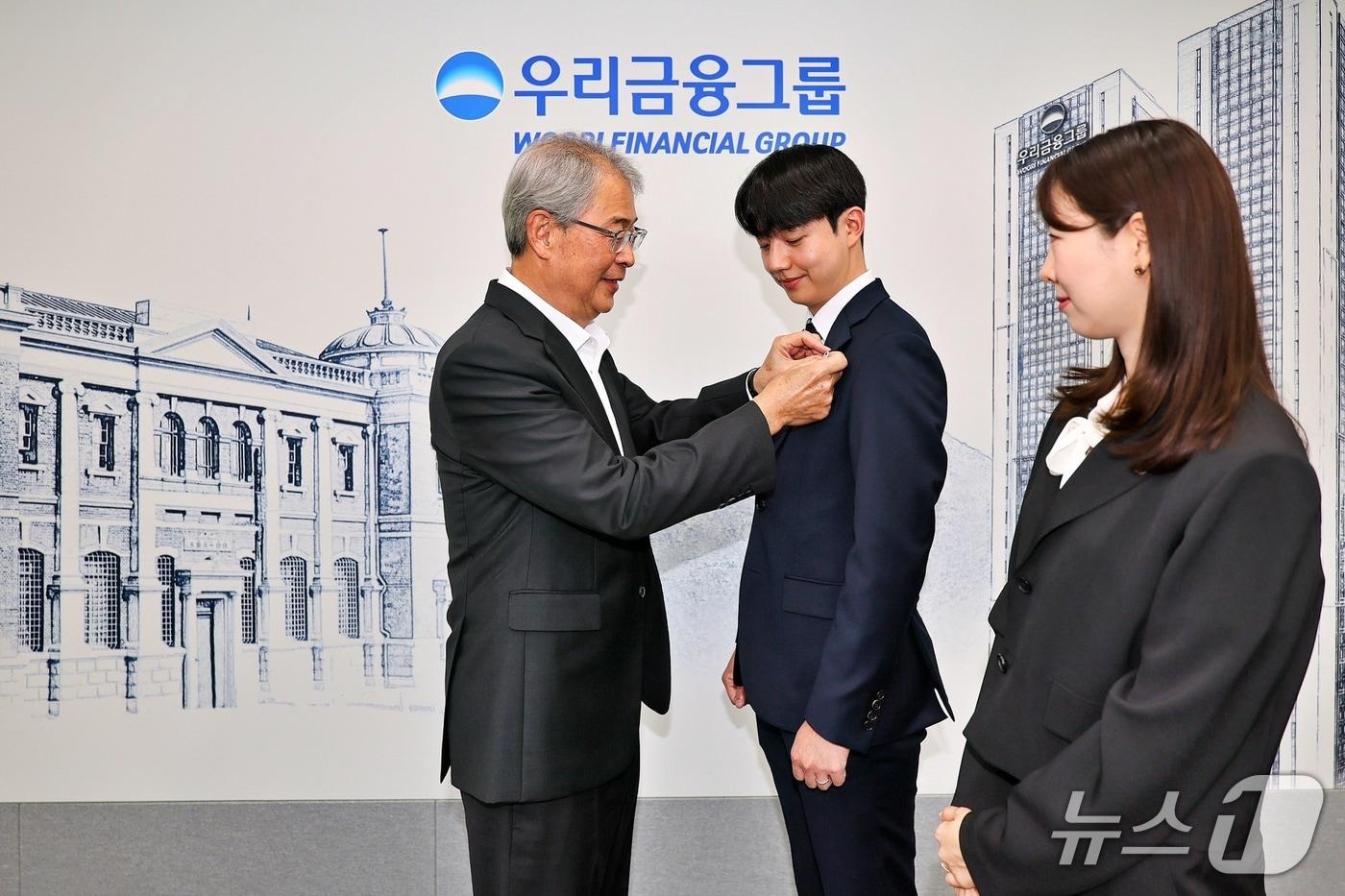 우리금융그룹 임종룡 회장이 그룹의 새 가족이 된 동양생명·ABL생명 직원에게 디지털 선도의 의미가 담긴 새로운 그룹 보조휘장을 달아주고 있다./사진제공=우리금융그룹