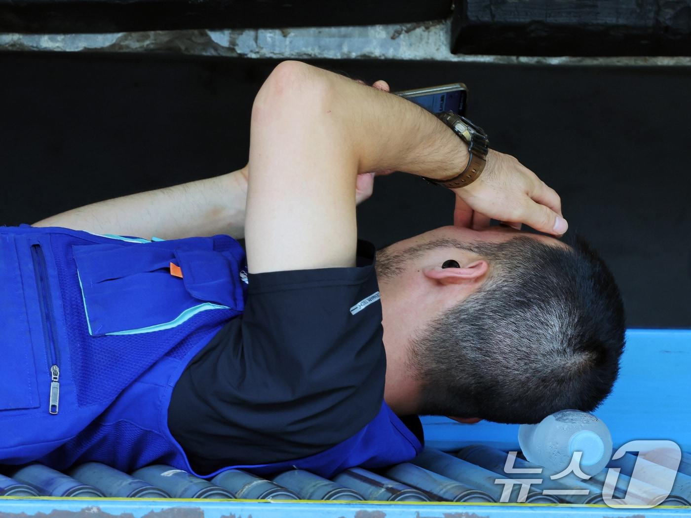 본문 이미지 - 연일 폭염이 이어지고 있는 9일 서울 시내 한 택배물류센터에서 노동자가 택배 분류 작업 중 휴식을 취하고 있다. 2025.7.9/뉴스1 ⓒ News1 황기선 기자