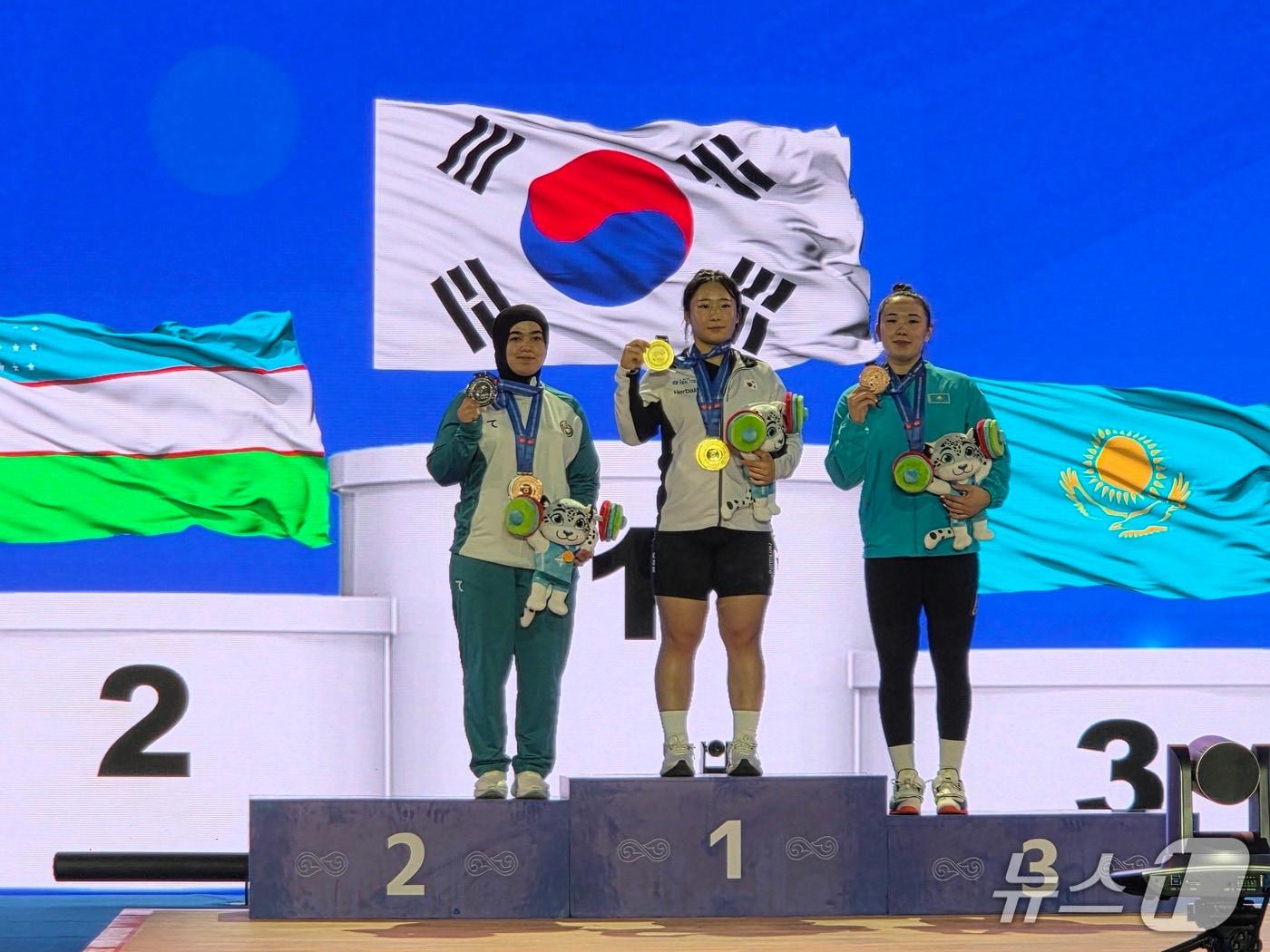 본문 이미지 - 전희수가 8일(현지시간) 열린 아시아주니어 역도 선수권 여자 77㎏급에서 3관왕을 달성한 뒤 시상대에 올라 기념 촬영을 하고 있다. (대한역도연맹 제공)