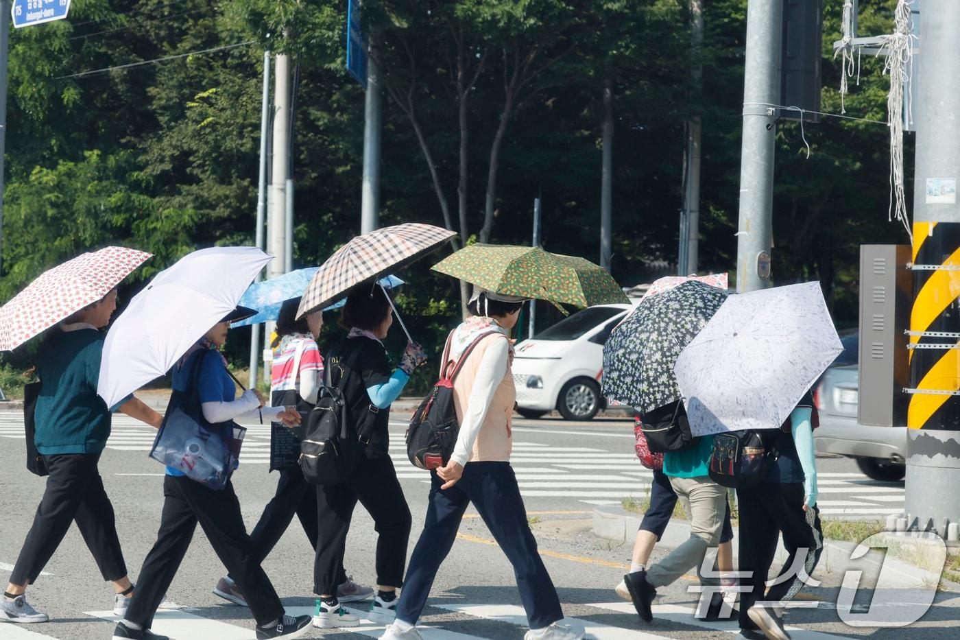 역대급 더위가 지속되고 있는 9일 광주 광산구 임방울도로 4거리에 시민들이 더위를 피해 양산을 쓰고 걸어가고 있다. 2025.7.9/뉴스1 ⓒ News1 김태성 기자