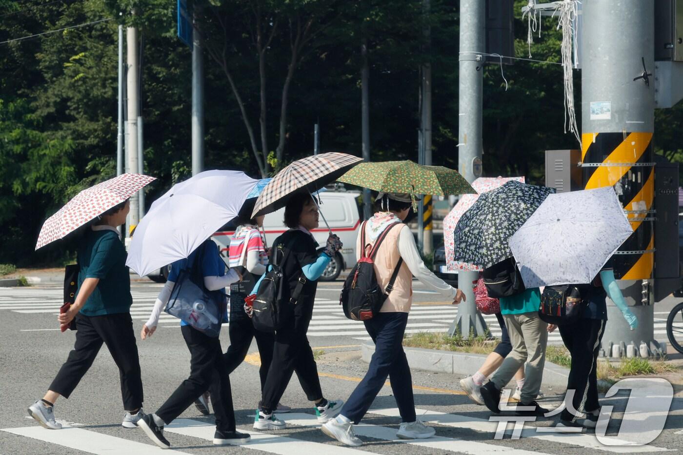 역대급 더위가 지속되고 있는 9일 광주 광산구 임방울도로 사거리에서 시민들이 더위를 피해 양산을 쓰고 걸어가고 있다. 2025.7.9/뉴스1 ⓒ News1 김태성 기자