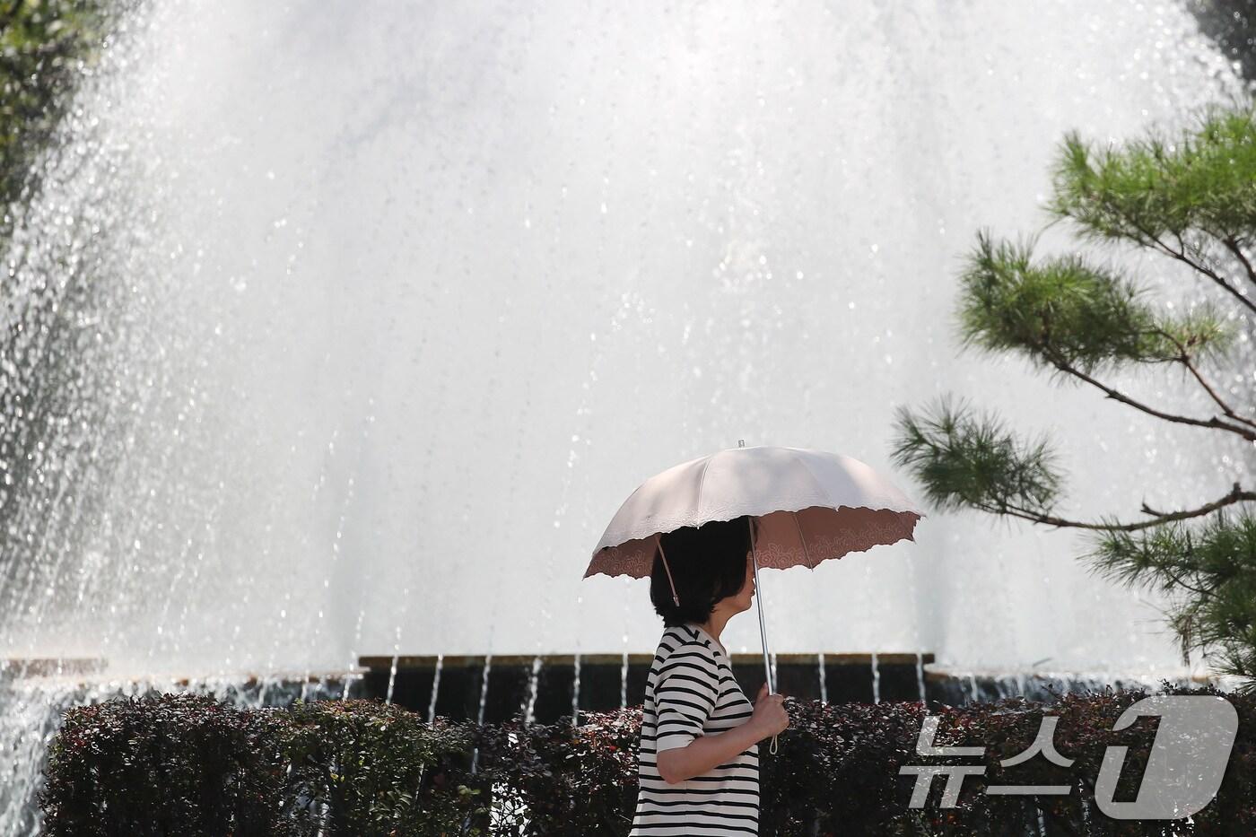 대구 중구 대구시청 동인청사 앞에서 한 시민이 양산을 펼쳐 뙤약볕을 가린 채 분수대를 지나고 있다. 2025.8.1/뉴스1 ⓒ News1 공정식 기자