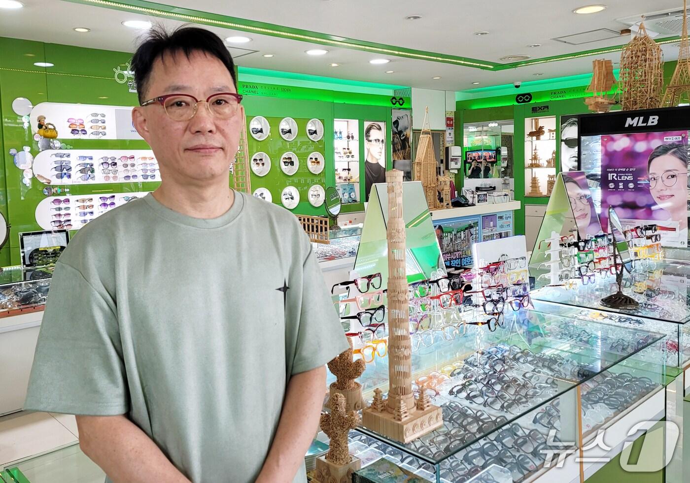 수눌음안경원 사장 여호근 씨. 뒤로 그가 이쑤시개로 제작한 작품들이 보인다. 