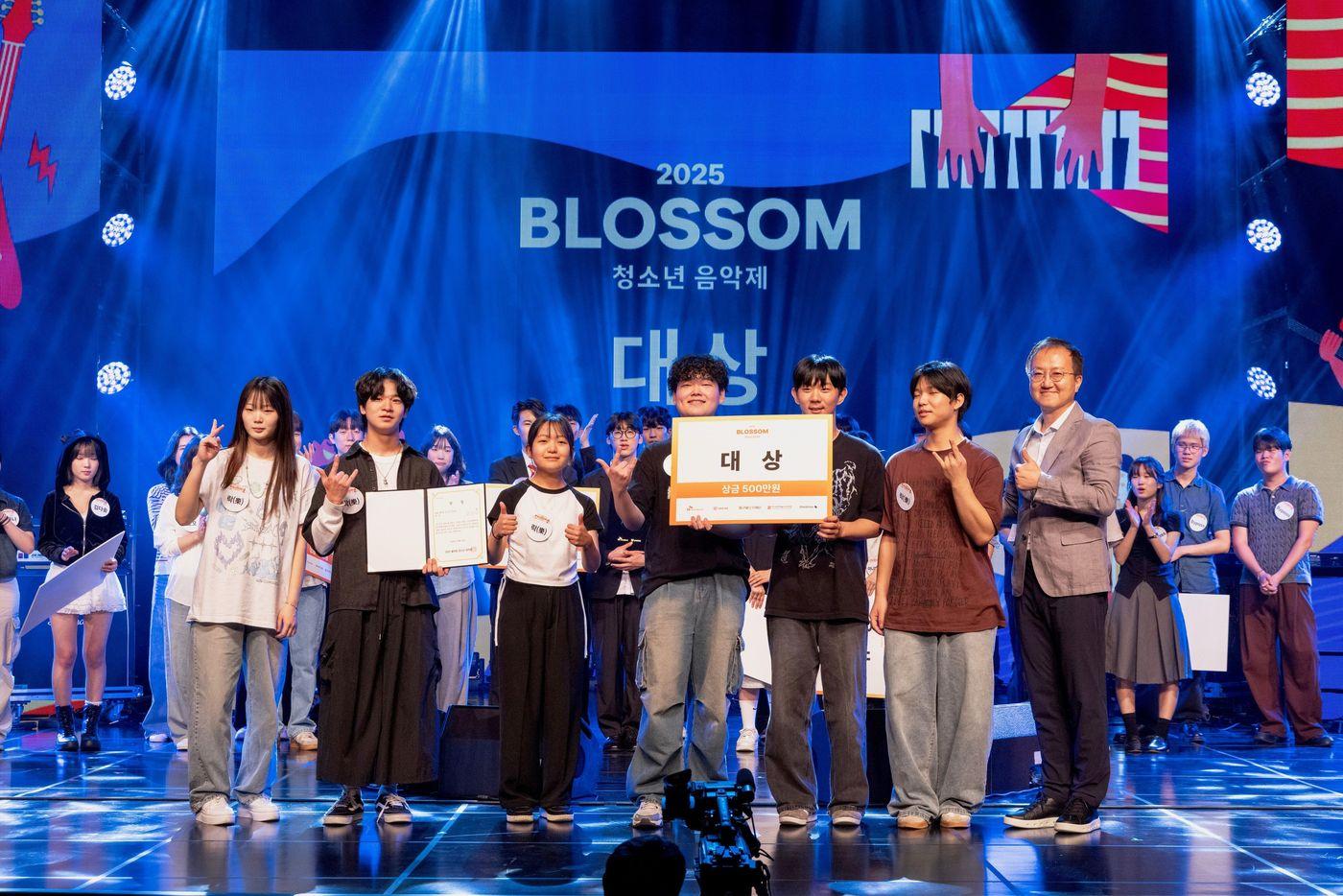 SK브로드밴드는 지난 9일 오후 서울 구로 아트밸리에서 개최한 '2025 블러썸 청소년 음악제'를 성황리에 마쳤다고 11일 밝혔다. 시상식에서 대상을 수상한 ‘락(樂)밴드’와 김지훈 SK브로드밴드 경영전략실장(맨 오른쪽)이 기념 촬영하는 모습. (SKB 제공)