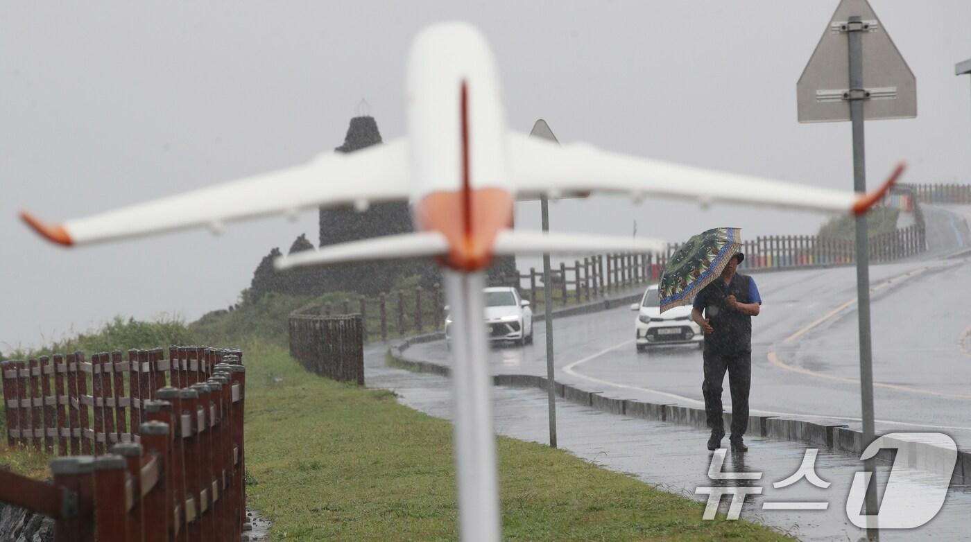 제주에 비가 내리면서 폭염특보가 모두 해제된 11일 오전 제주시 용담해안도로에서 우산을 쓴 행인이 발걸음을 옮기고 있다. 2025.8.11/뉴스1 ⓒ News1 오현지 기자
