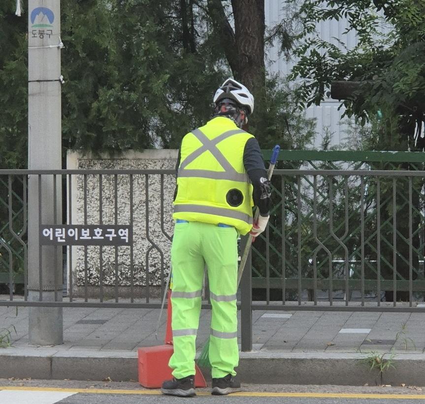 본문 이미지 - 도봉구 야외 청소 현업근로자가 선풍기 조끼를 입고 도봉구 지역 내 한 도로를 청소하고 있다.(도봉구 제공)