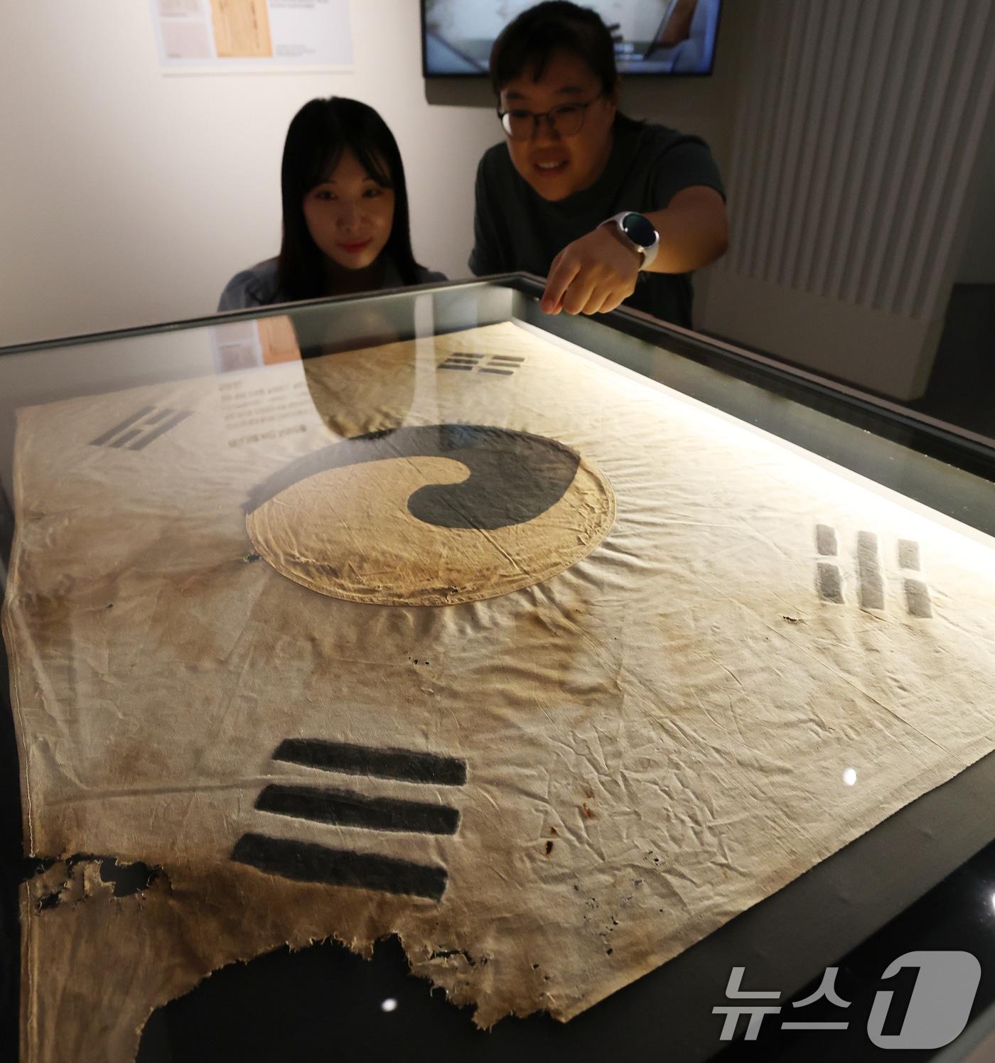 본문 이미지 - 11일 오전 서울 중구 덕수궁 돈덕전에서 열린 '빛을 담은 항일유산' 특별전 언론공개회에서 방문객들이 일제강점기 당시 일장기를 먹으로 덧칠해 만든 '서울 진관사 태극기'를 살펴보고 있다. 국가유산청이 광복 80주년을 맞아 개항기부터 대한제국, 일제강점기, 광복에 이르는 시대를 110여 점의 유물을 소개하는 이번 전시는 오는 12일부터 두 달간 개최된다. 2025.8.11/뉴스1 ⓒ News1 오대일 기자