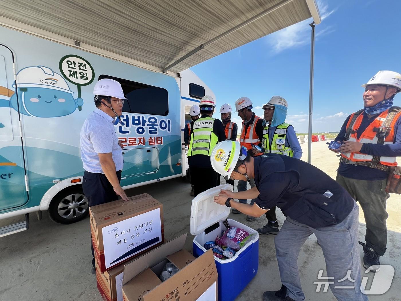 본문 이미지 - 송산그린시티 남측지구 공사 현장에 설치된 근로자 쉽터(이동형 휴게시설)에서 근로자들에게 폭염 대비 온열 예방 물품이 전달되고 있다. 왼쪽이 이상희 한국수자원공사 도시본부장. (한국수자원공사 제공.재판매 및 DB 금지)/뉴스1
