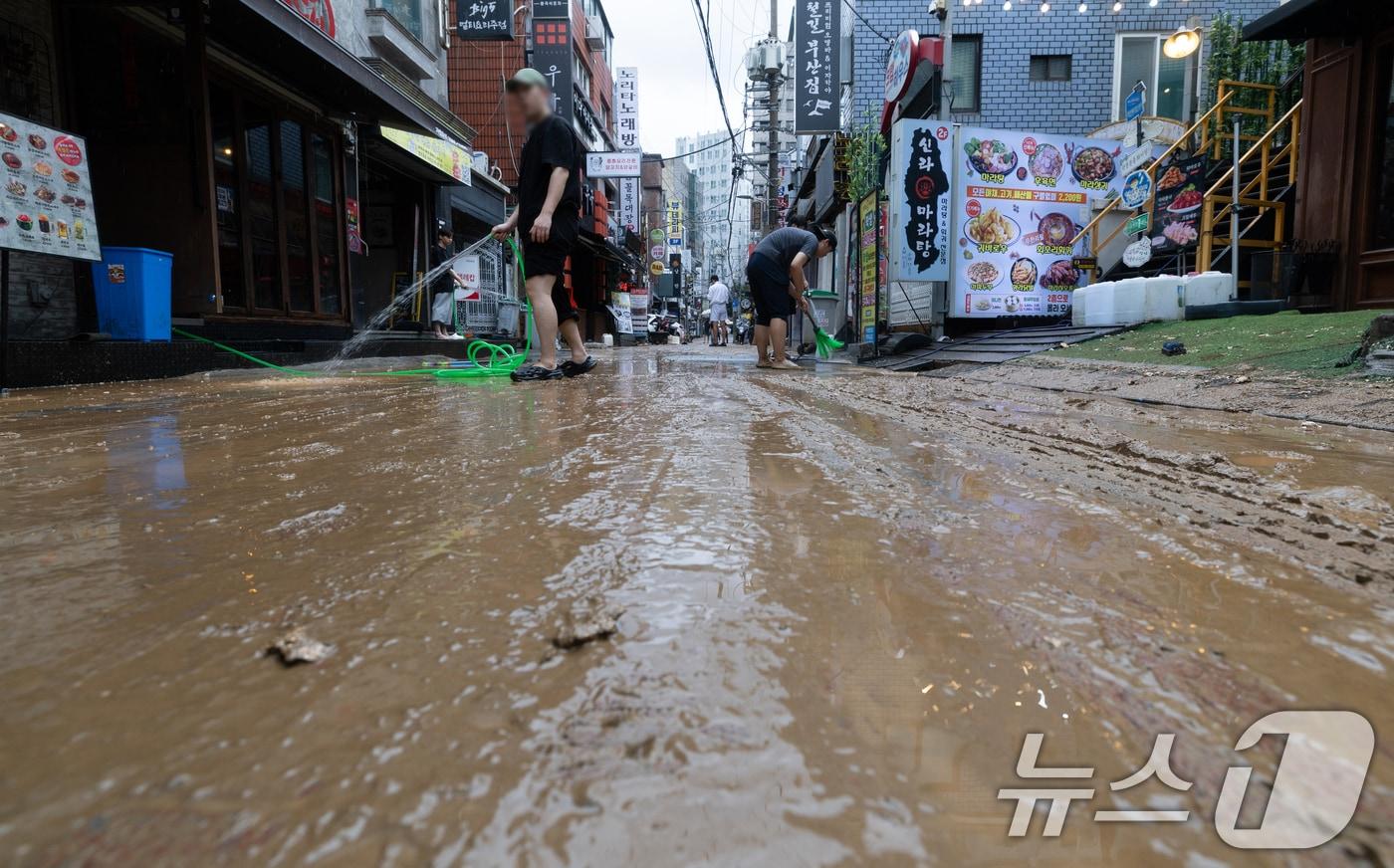 13일 오후 서울 은평구 연신내역 인근 상가 거리에서 상인들이 폭우로 인해 더러워진 거리를 청소하고 있다. 2025.8.13/뉴스1 ⓒ News1 이승배 기자