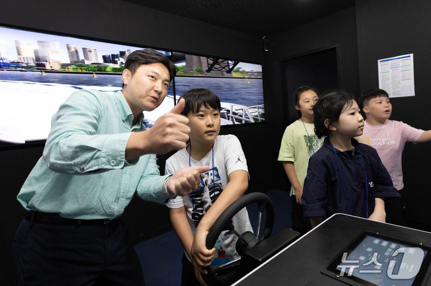 본문 이미지 - 상선체험 활동에 참여한 어린이들이 13일 HMM오션서비스 트레이닝센터에서 선박 조종 시뮬레이션을 체험하고 있다. &#40;HMM 제공&#41;