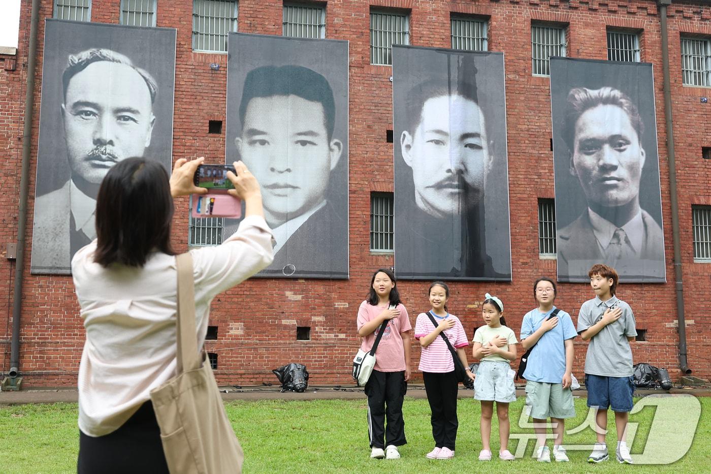 제80주년 광복절을 하루 앞둔 14일 서울 서대문형무소역사관을 찾은 어린이들이 독립운동가들의 모습을 담은 현수막을 배경으로 기념촬영을 하고 있다. 2025.8.14/뉴스1 ⓒ News1 민경석 기자