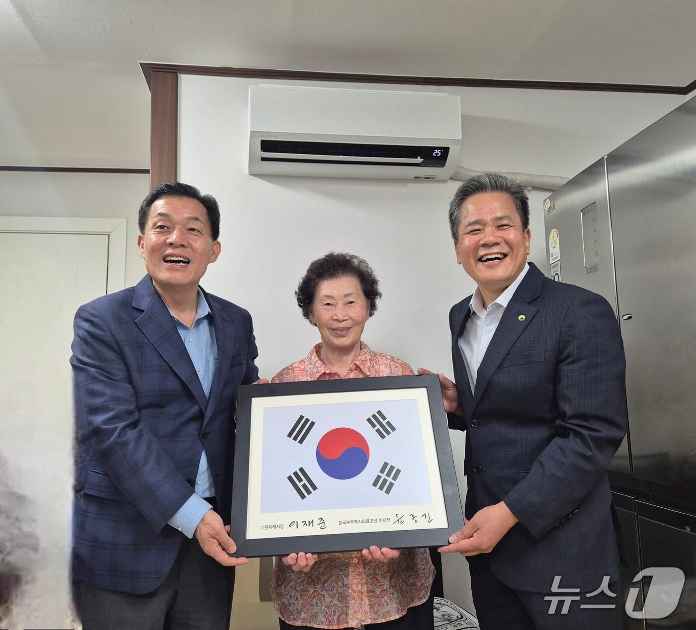 본문 이미지 - 한국보훈복지의료공단과 경기 수원시가 지난 14일 수원시 소재 강익승 애국지사 후손의 집에서 국가유공자를 위한 주거환경개선 공사의 준공 기념 행사를 갖고, 태극기를 전달하고 있다. &#40;한국보훈복지의료공단&#41; 2025.8.15/뉴스1