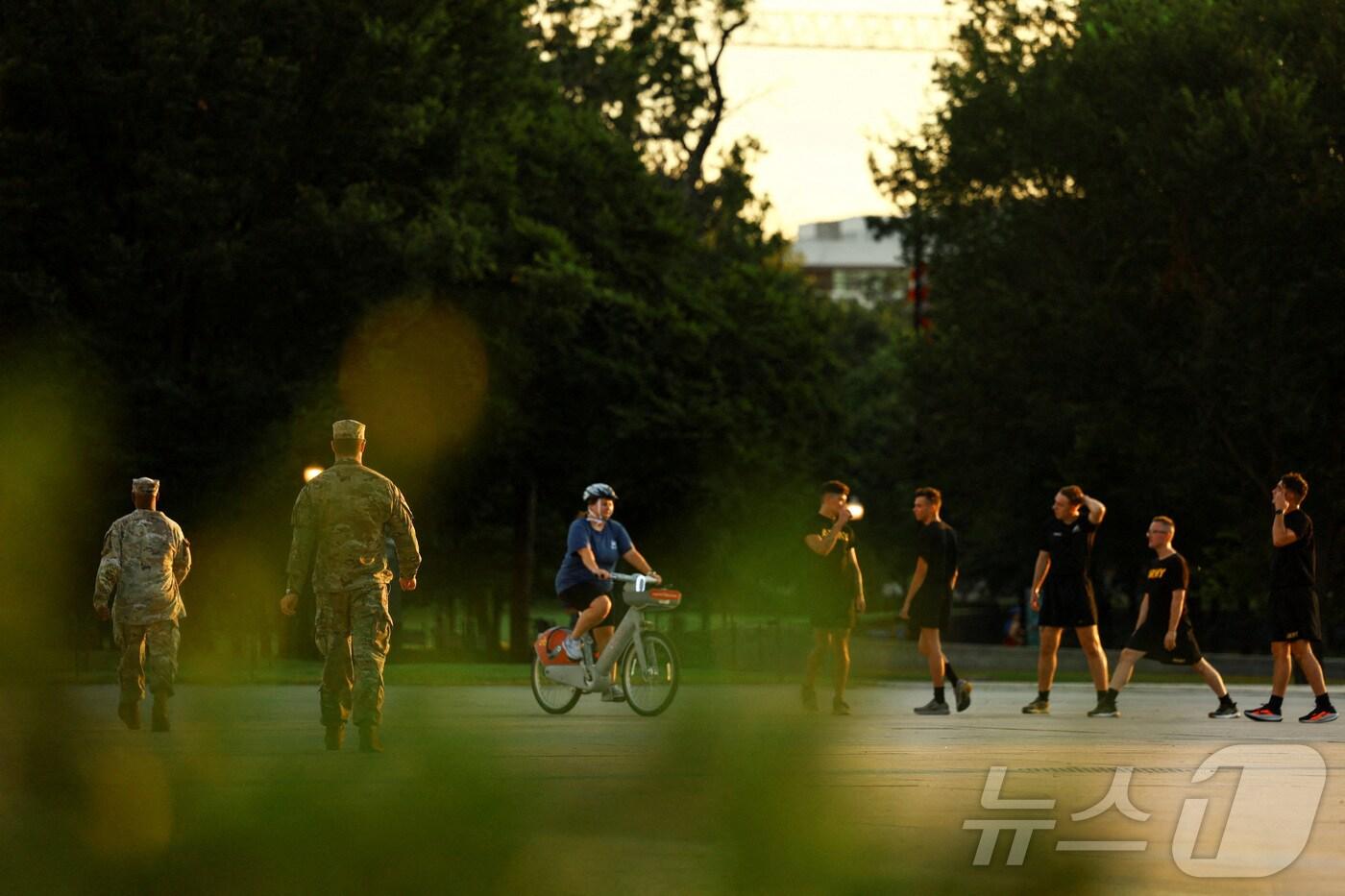 미국 군인들이 14일 워싱턴DC의 한 거리에서 운동하는 사람들 근처를 지나가고 있다. 도널드 트럼프 미국 대통령은 워싱턴DC 메트로폴리탄 경찰청의 연방 관할권을 발표하고, 수도의 범죄 예방을 돕는다는 명목으로 주 방위군을 배치했다. 2025.8.14 ⓒ 로이터=뉴스1 ⓒ News1 강민경 기자