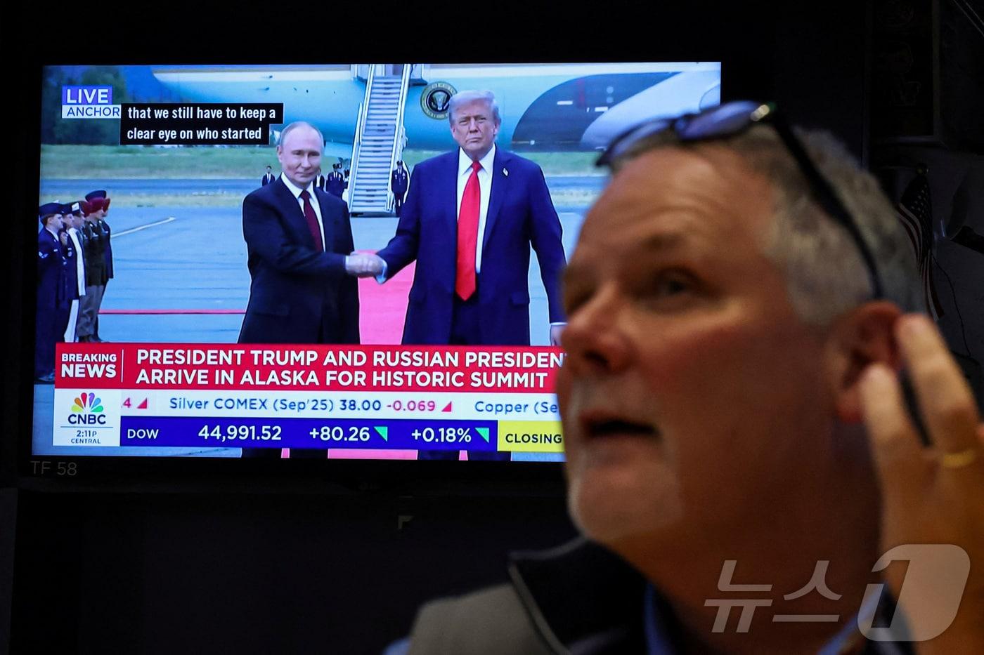 15일&#40;현지시간&#41; 뉴욕증권거래소&#40;NYSE&#41; 현장에서 미국 대통령 도널드 트럼프가 러시아 대통령 블라디미르 푸틴과 인사를 나누는 모습을 트레이더들이 지켜보고 있다.2025.8.15 ⓒ 로이터=뉴스1