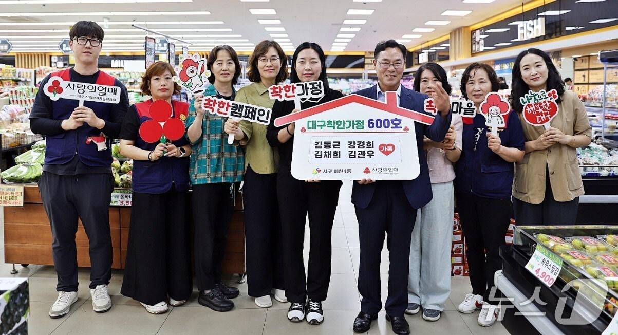 본문 이미지 - 대구사회복지공동모금회가 선정하는 '대구 착한가정' 600호가 나왔다. 주인공은 서구 비산4동에서 세종마트를 운영하는 김동근·강경희 씨 부부(사진 가운데 '착한가정' 팻말을 든 2명)다. (대구사회복지공동모금회 제공. 재판매 및 DB 금지)/뉴스1