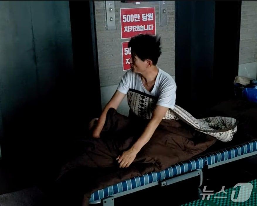 본문 이미지 - 김건희특검의 국민의힘 당사 압수수색을 저지하기 위해 여의도 국민의힘 중앙당사 1층 로비에서 농성 중인 김문수 당 대표 후보가 18일 아침,  속옷 차림으로 일어나 주위를 살피고 있다. (김문수TV 갈무리) ⓒ 뉴스1 