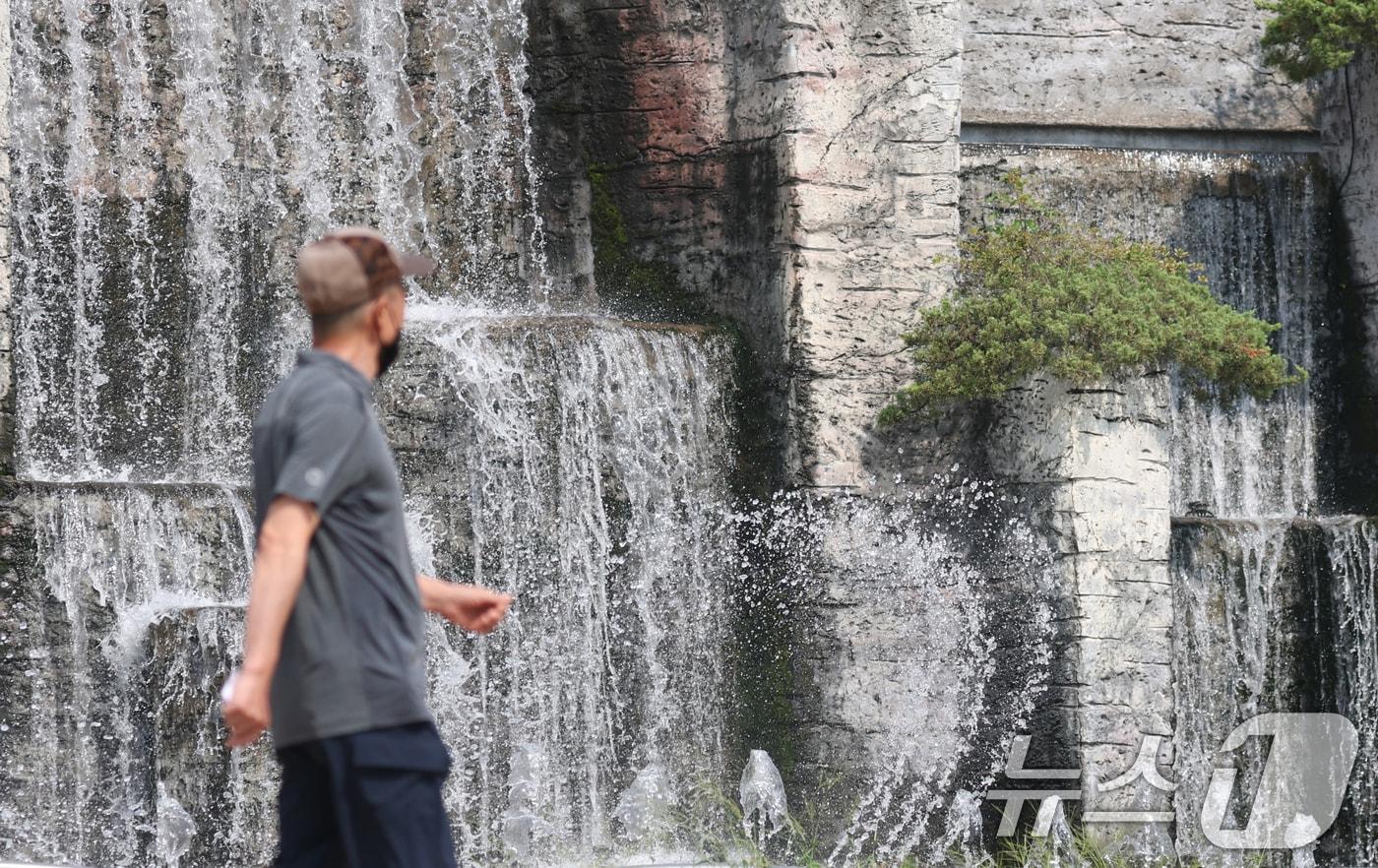 전국 대부분 지역에 폭염 경보나 주의보가 이어지고 있는 가운데 18일 오후 경기 오산시 수청공원에서 시민들이 시원하게 쏟아지는 폭포 앞으로 지나가고 있다. 2025.8.18/뉴스1 ⓒ News1 김영운 기자