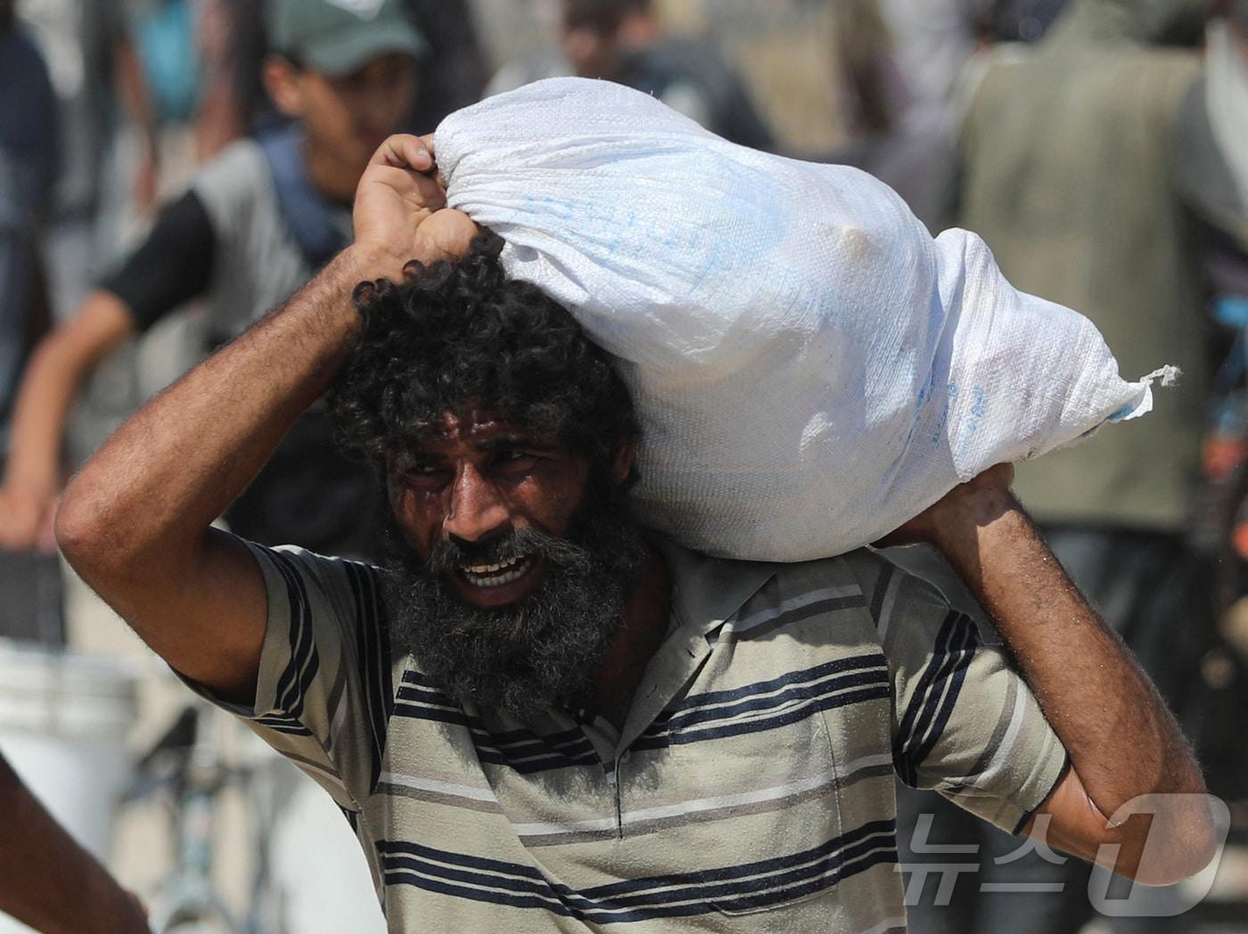 본문 이미지 - 2025년 8월 1일 가자지구 북부 베이트라히아에서 한 팔레스타인 주민이 이스라엘을 통해 가자에 들어온 구호 물품이 담긴 가방을 들고 걷고 있다. 2025.8.1 ⓒ 로이터=뉴스1 ⓒ News1 강민경 기자