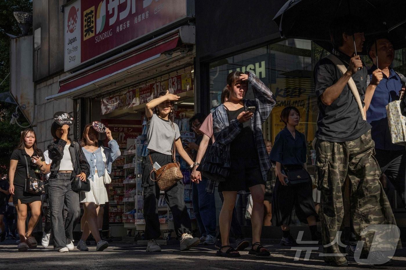 7월 26일&#40;현지시간&#41; 도쿄의 한 거리에서 시민들이 따가운 햇볕을 피해 눈을 가린 채 걷고 있다. 2025.07.26. ⓒ AFP=뉴스1 ⓒ News1 윤다정 기자