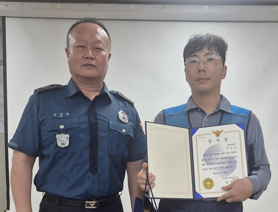 본문 이미지 - 이석호 서울동작우체국 집배원(오른쪽)이 19일 보이스피싱 범죄예방 기여 공로로 하영일 서울남성지구대장에게 감사장을 받고 기념 촬영을 하고 있다.(서울지방우정청 제공)