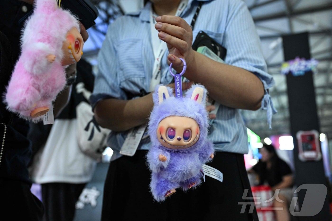 2025년 8월 4일 상하이 신국제박람센터에서 열린 중국 디지털 엔터테인먼트 박람회 &#39;차이나조이&#40;ChinaJoy&#41;&#39;에서 한 여성이 라부부 인형을 방문객들에게 판매하고 있다. ⓒ AFP=뉴스1