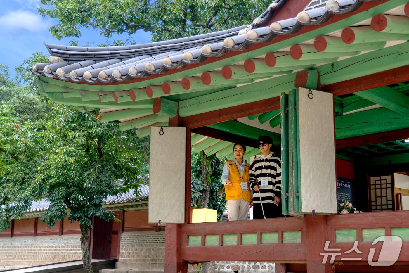 궁궐을 둘러보고 있는 현장영상해설사와 시각장애인 참가자&#40;서울관광재단 제공&#41;