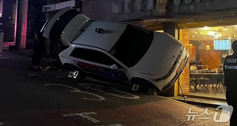 본문 이미지 - 21일 오후 6시 47분쯤 서울 마포구 한 상점가에 돌진한 택시가 비스듬히 멈춰 서있다.(독자제공)