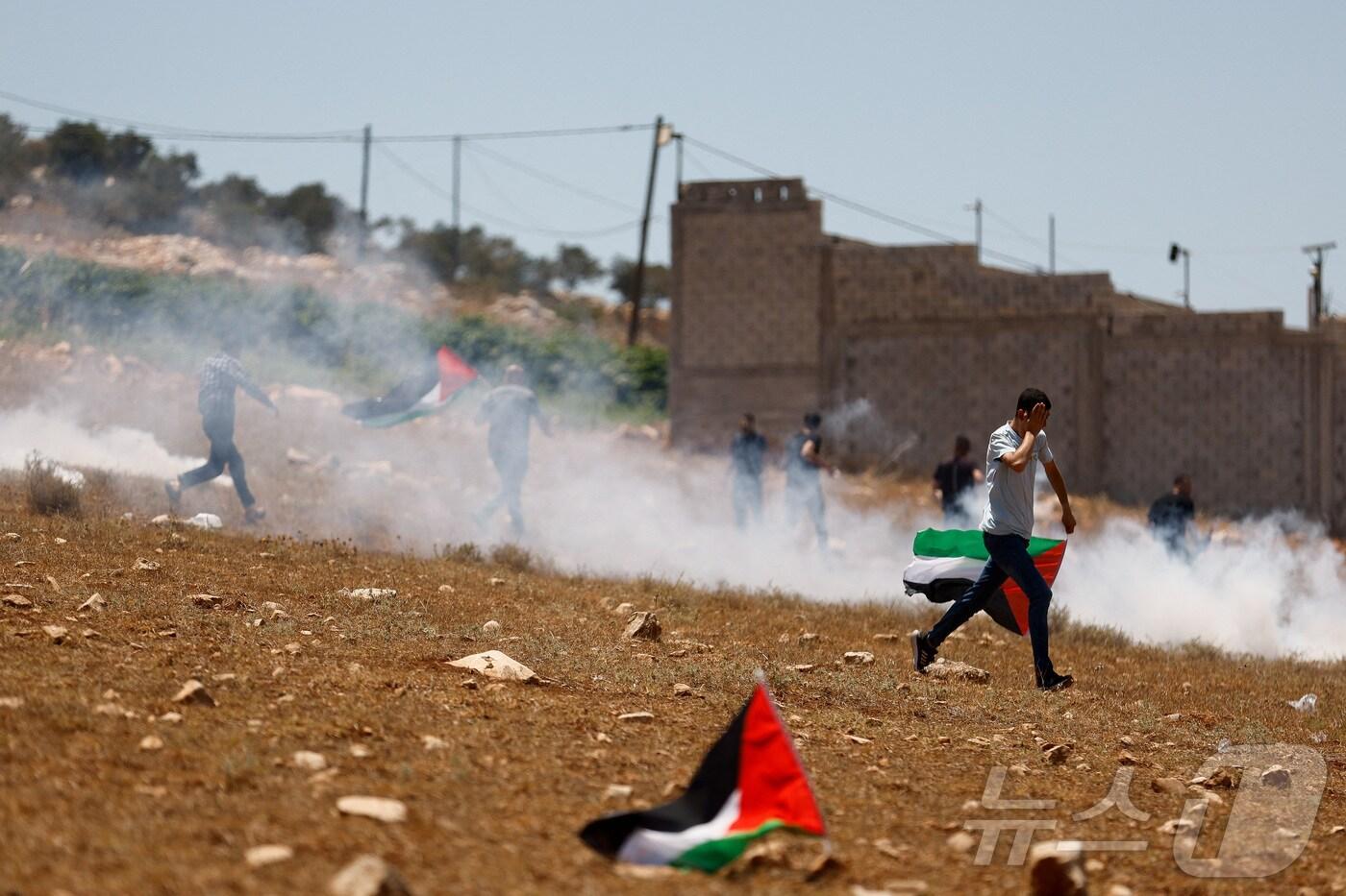 이스라엘이 점령한 서안지구 제닌 근처 라바에서 시위를 벌이고 있는 팔레스타인인들과 경계를 서고 있는 이스라엘군. 2025.7.18 ⓒ 로이터=뉴스1 ⓒ News1 김경민 기자