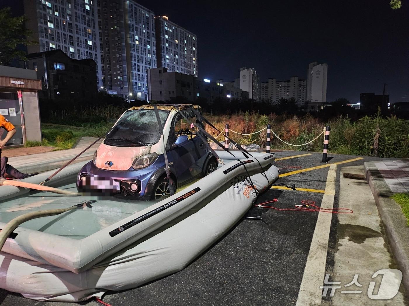 본문 이미지 - 소방당국은 불에 탄 차량을 인근 공터에 이동식 대형 수조를 설치, 차량을 물에 담가 완전히 불을 껐다.(제천소방서 제공, 재판매 및 DB금지)/뉴스1 