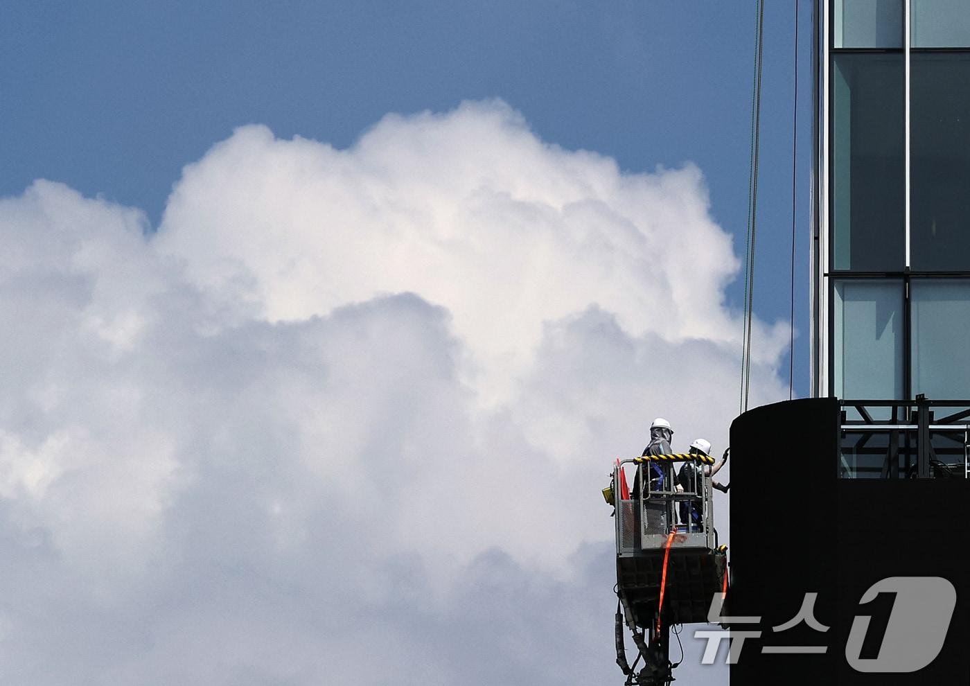 한국판 타임스스퀘어를 표방하는 광화문스퀘어 조성 사업이 본격화한 가운데 24일 오후 서울 종로구 KT 광화문 웨스트 사옥 외벽에서 노동자들이 새하얀 뭉게구름을 배경으로 대형 전광판 설치 작업에 한창이다. /뉴스1 ⓒ News1 오대일 기자