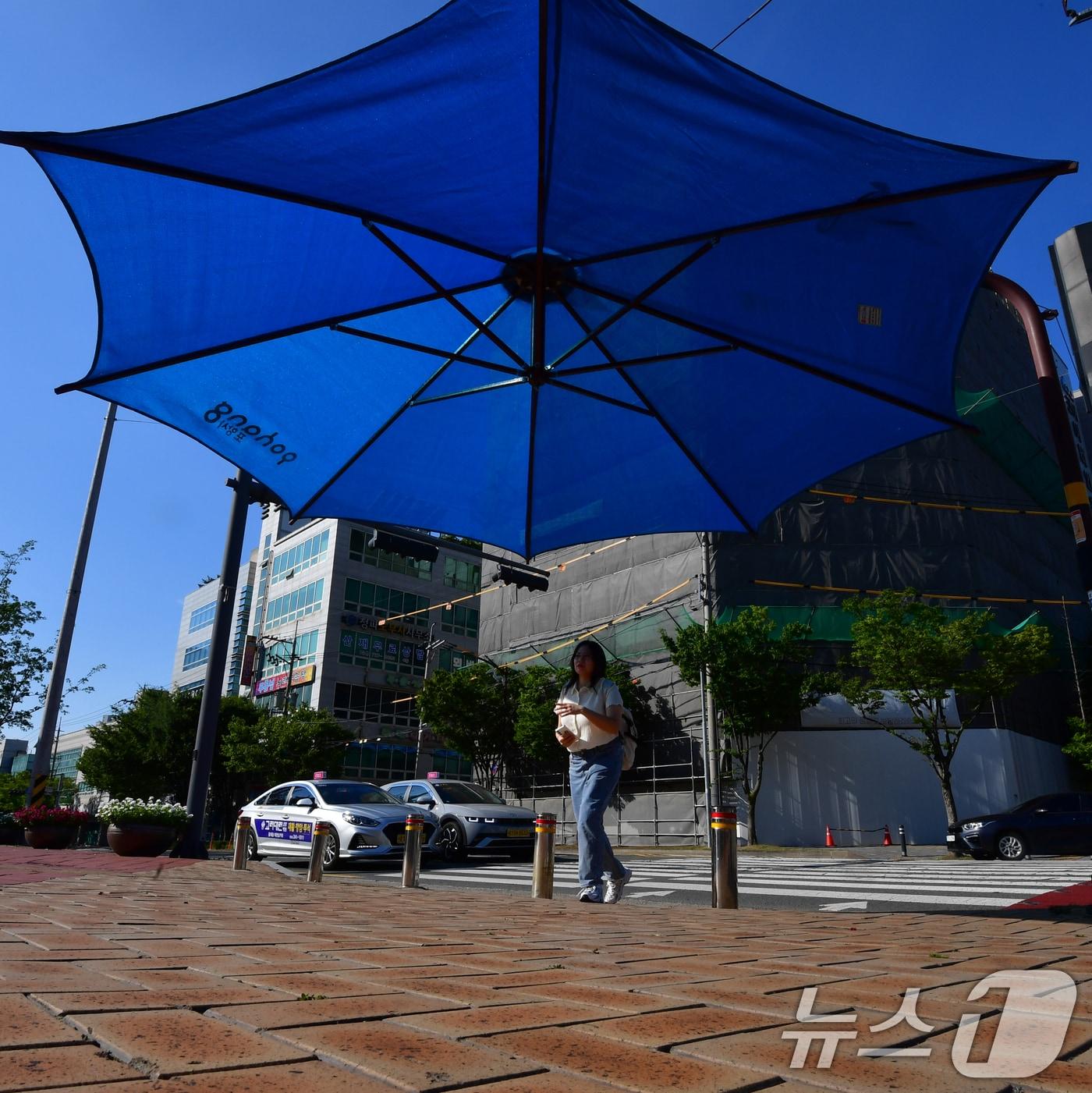 본문 이미지 - 26일 경북 포항시 전역에 폭염특보가 발효 중인 가운데 출근길에 나선 시민이 포항시청 앞 횡단보도에 설치된 대형 우산 그늘막 아래로 걸어가고 있다. 2025.8.26/뉴스1 ⓒ News1 최창호 기자