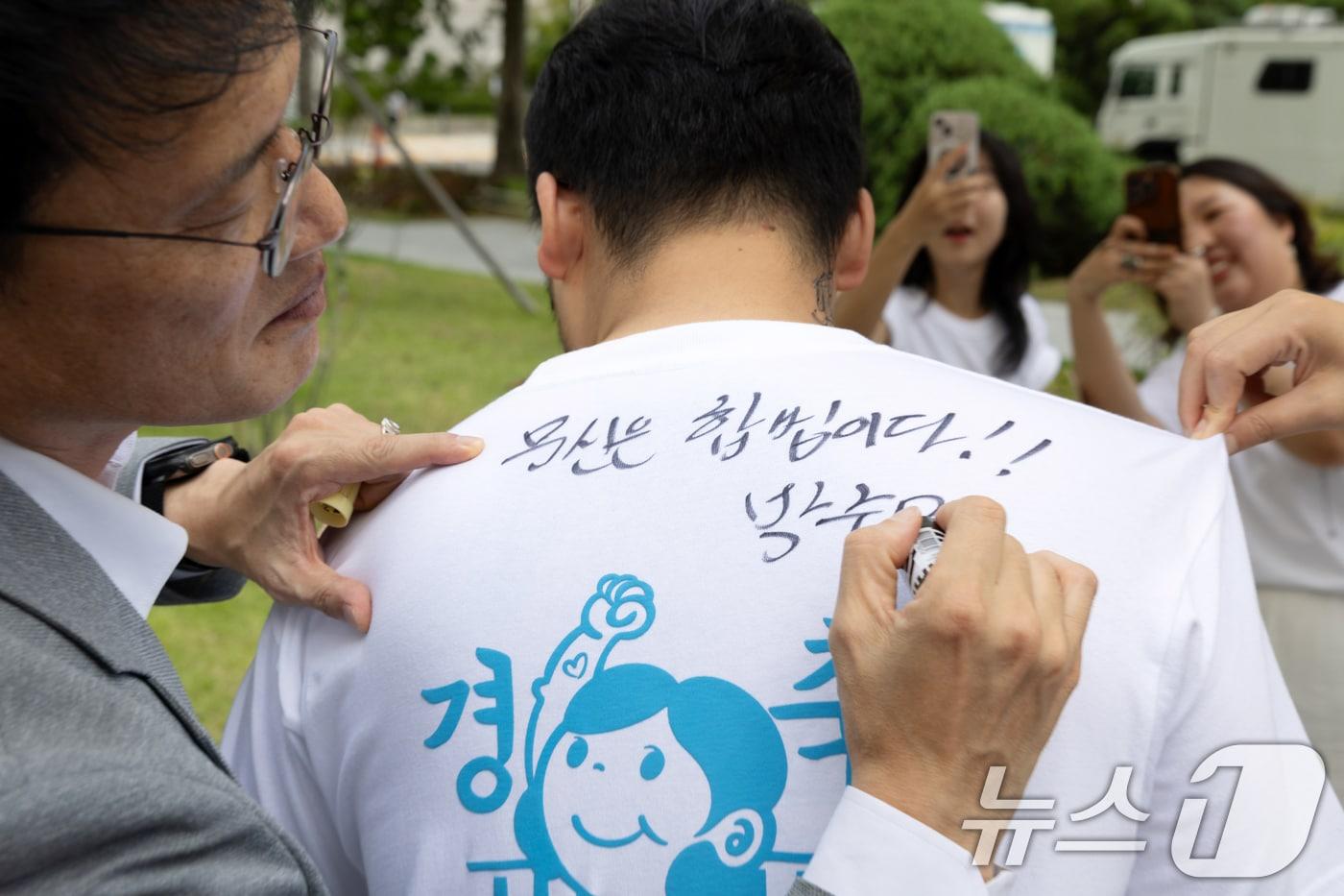 박주민 국회 보건복지위원장이 지난 8월 27일 서울 여의도 국회 소통관 앞에서 열린 '문신사법 의결 경축' 타투이스트들의 캐리커쳐 행사에 참석한 뒤 타투이스트의 티셔츠에 사인을 해주고 있다. (사진은 기사 내용과 무관함) 2025.8.27/뉴스1 ⓒ News1 이승배 기자