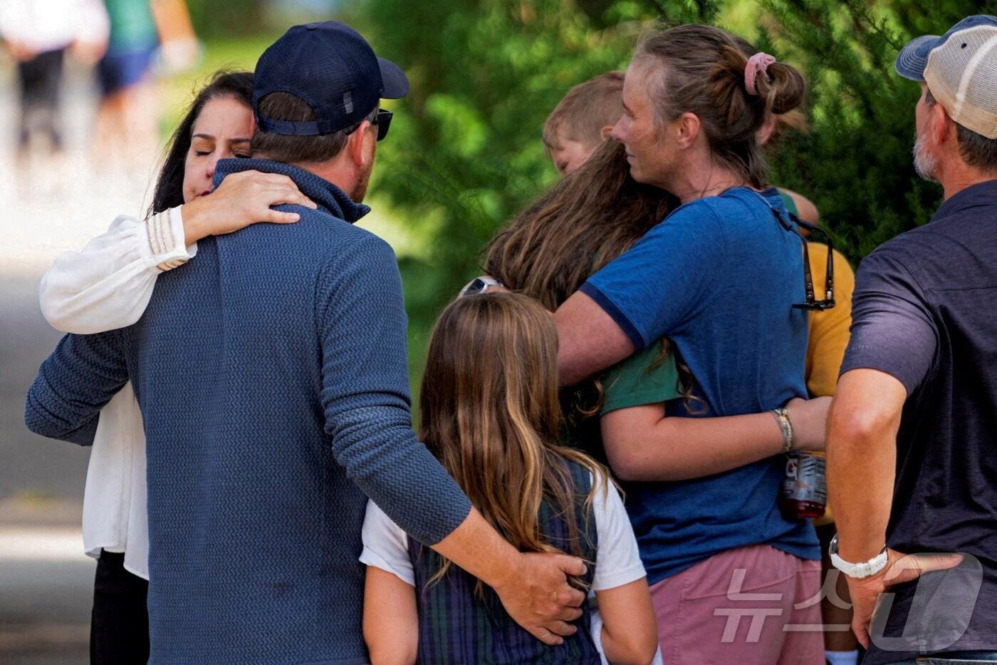 27일(현지시간) 미국 미네소타주 미니애폴리스의 어넌시에이션 성당과 부속 학교 인근 총격 현장에서 시민들이 서로를 다독이며 위로하고 있다. 2025.8.28 ⓒ AFP=뉴스1 ⓒ 로이터=뉴스1