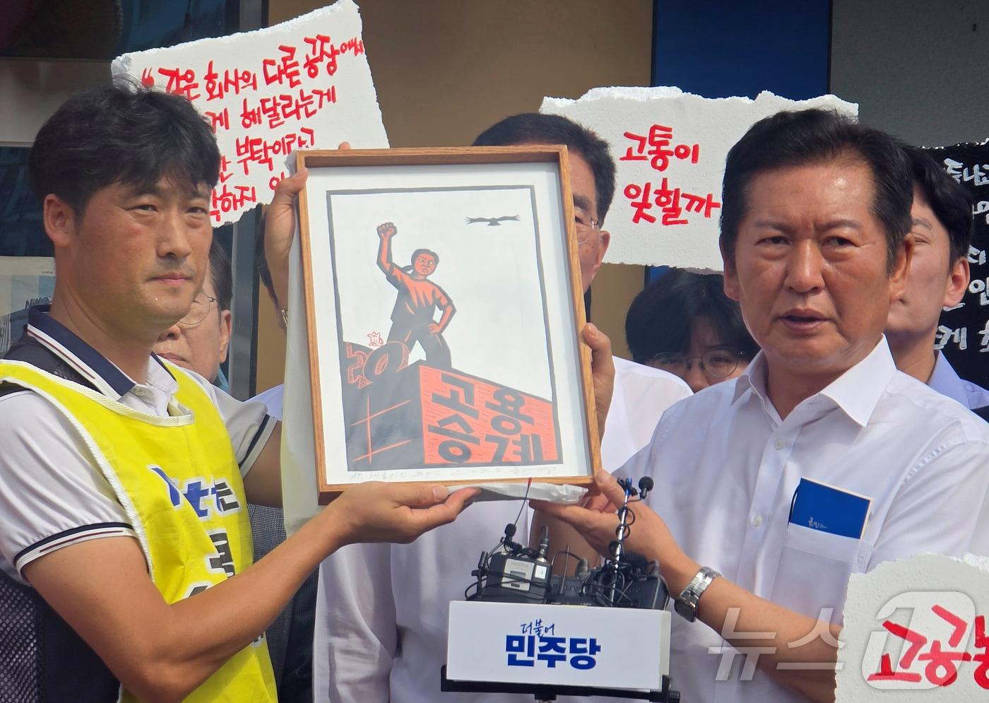 정청래 더불어민주당 대표가 28일 구미시 한국옵티칼하이테크를 방문해 599일째 고공농성 중인 박정혜 금속노조 한국옵티칼하이테크지회 수석부지회장과 면담한 후 노조원들으로부터 '고용승계'가 적힌 액자를 받고 있다.2025.08.28/뉴스1 ⓒ News1 정우용 기자