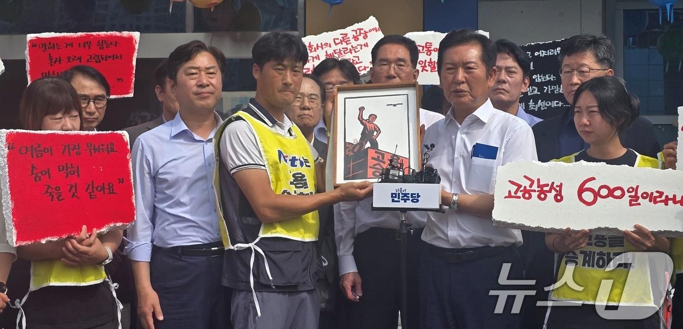 정청래 더불어민주당 대표가 28일 경북 구미시 한국옵티칼하이테크를 방문해 599일째 고공농성 중인 박정혜 금속노조 한국옵티칼하이테크지회 수석부지회장과 면담한 후 노조원들로부터 '고용승계'가 적인 그림액자를 선물받고 있다. 2025.08.28/뉴스1 ⓒ News1 정우용 기자