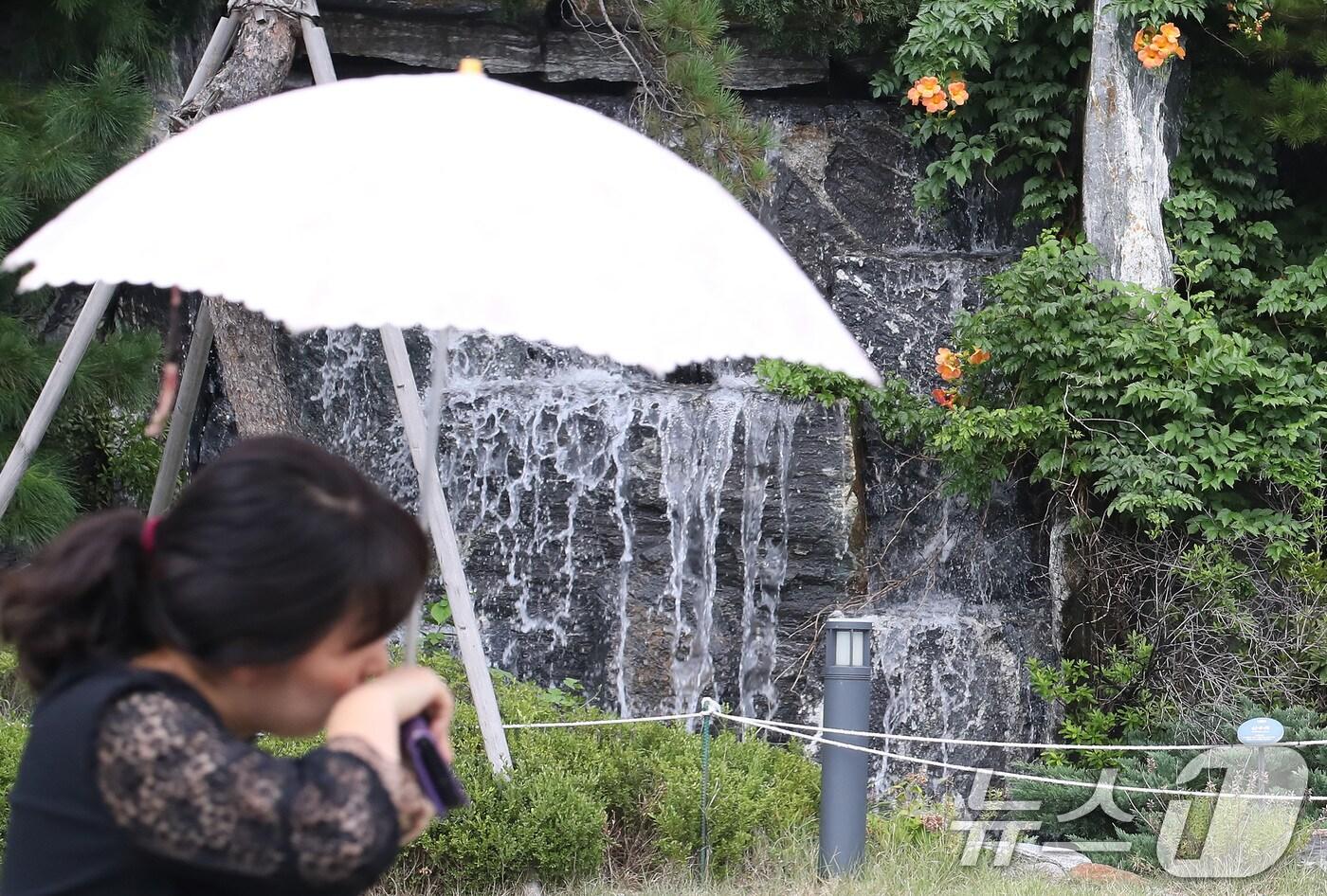 폭염이 계속된 지난 8월 28일 오후 대구 북구의 한 아파트 단지에서 양산을 쓴 시민이 인공폭포 앞을 지나고 있다. 뉴스1ⓒ News1 공정식 기자